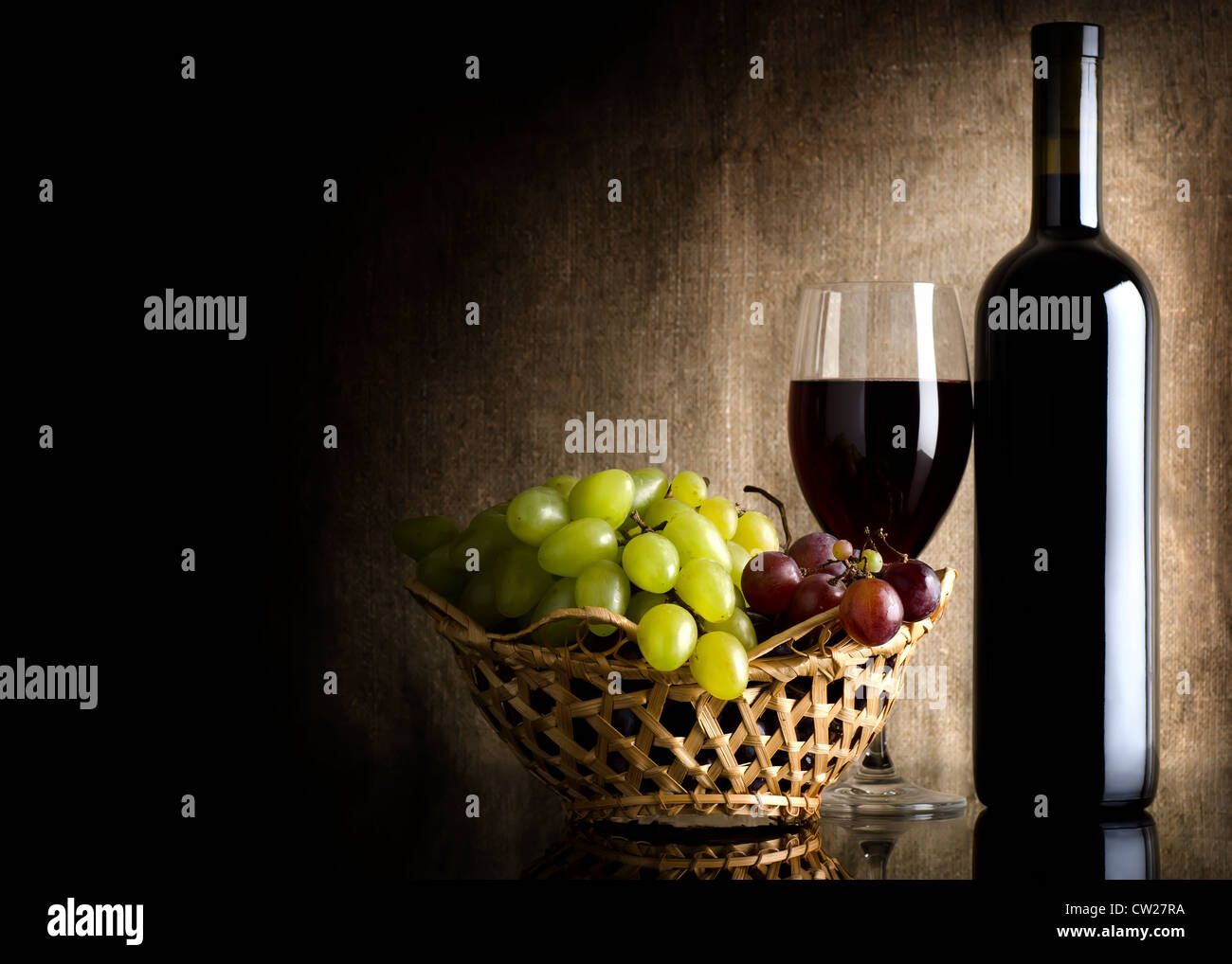 Bouteille de vin rouge et les raisins sur une toile de fond Banque D'Images