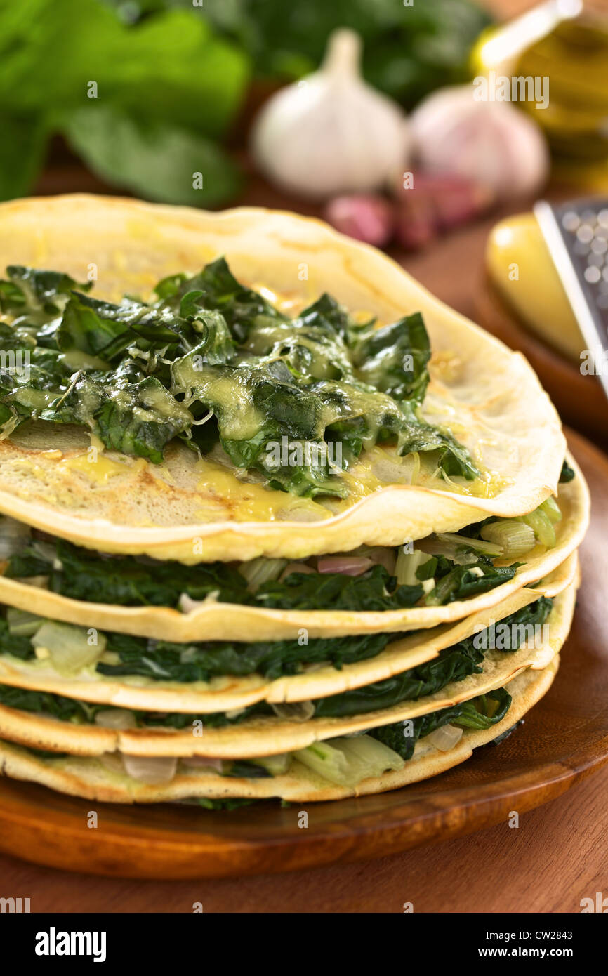 Crêpes salées fraîches maison posée avec cardes mangold) et l'oignon avec du fromage sur le dessus servi sur plaque en bois avec des ingrédients Banque D'Images