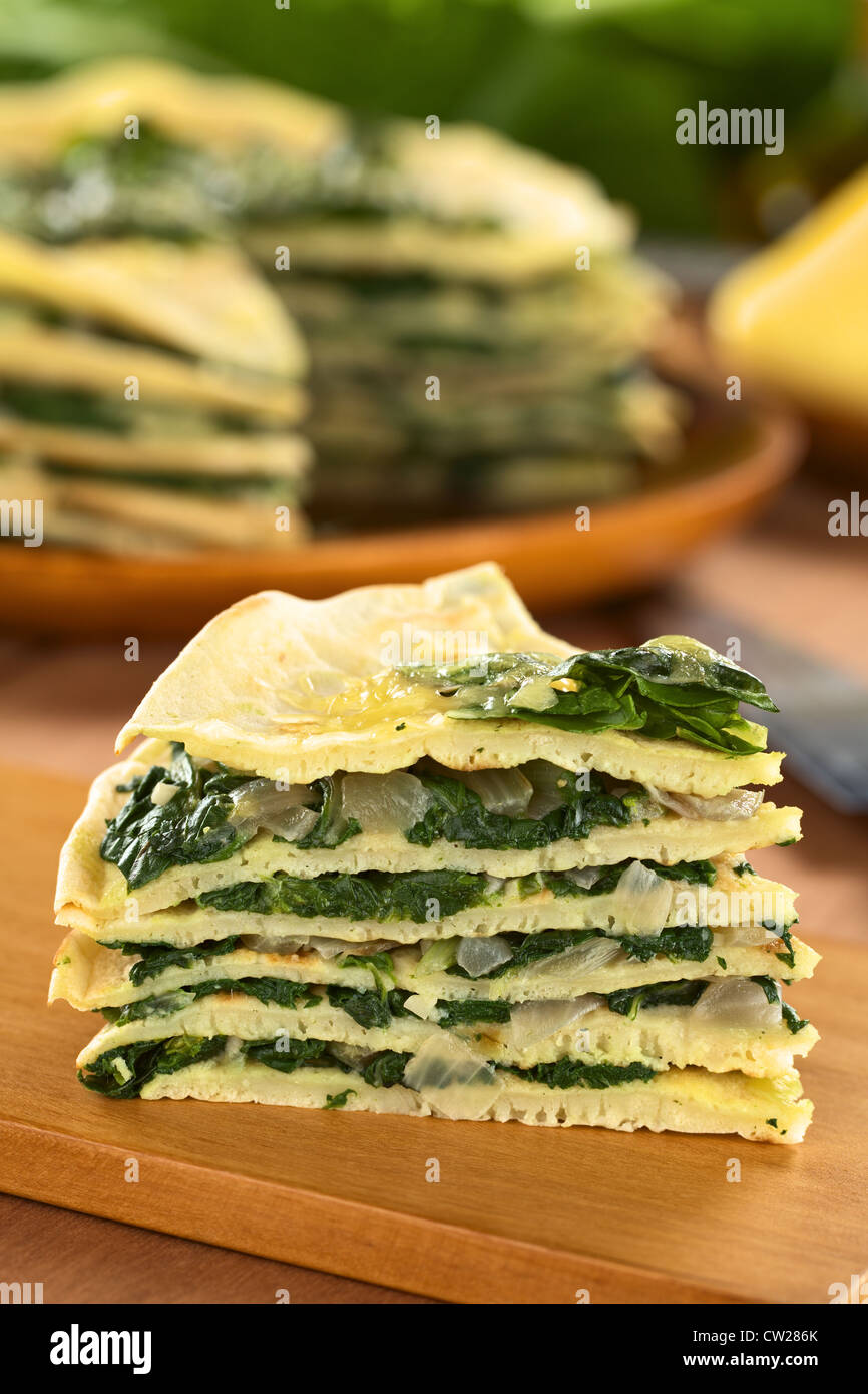 Un morceau de crêpes salées fraîches maison posée avec cardes mangold) et l'oignon avec du fromage sur le dessus sur planche de bois Banque D'Images