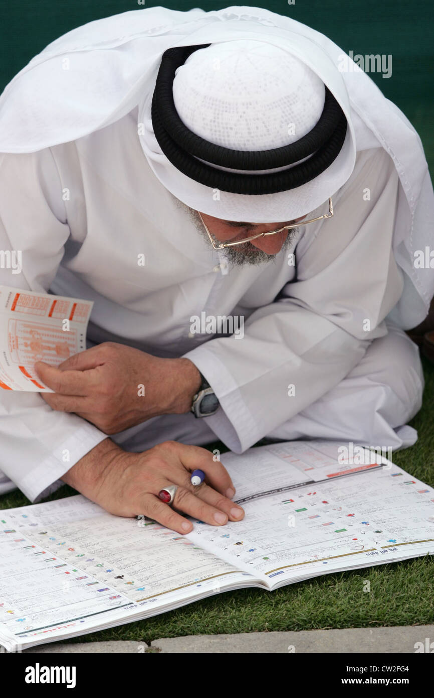 Dubaï, un homme à l'examen du programme des courses à l'Hippodrome Nad Al Sheba Banque D'Images