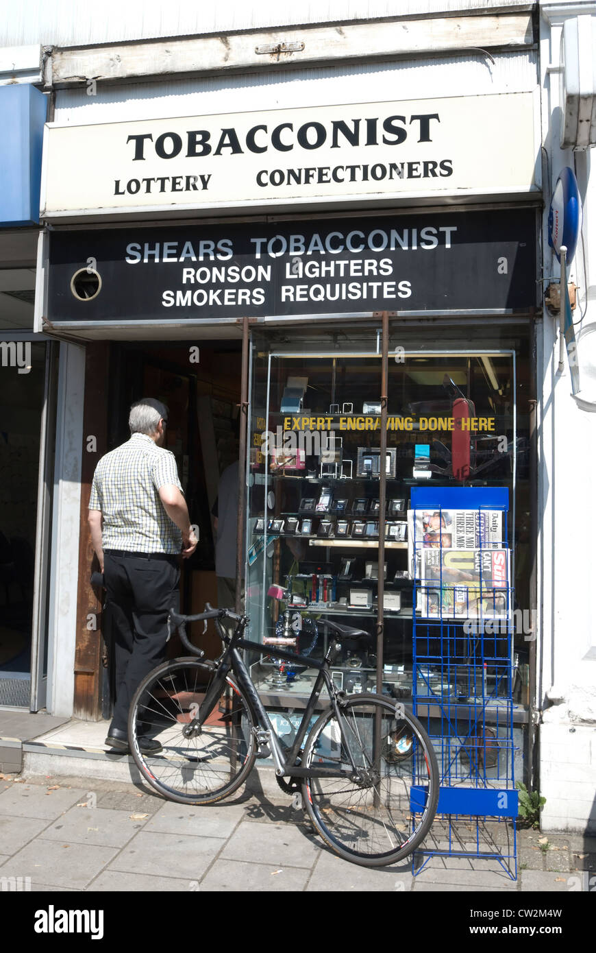 L'homme aux cheveux gris entrant dans un magasin de tabac, Chiswick, Londres, Angleterre Banque D'Images
