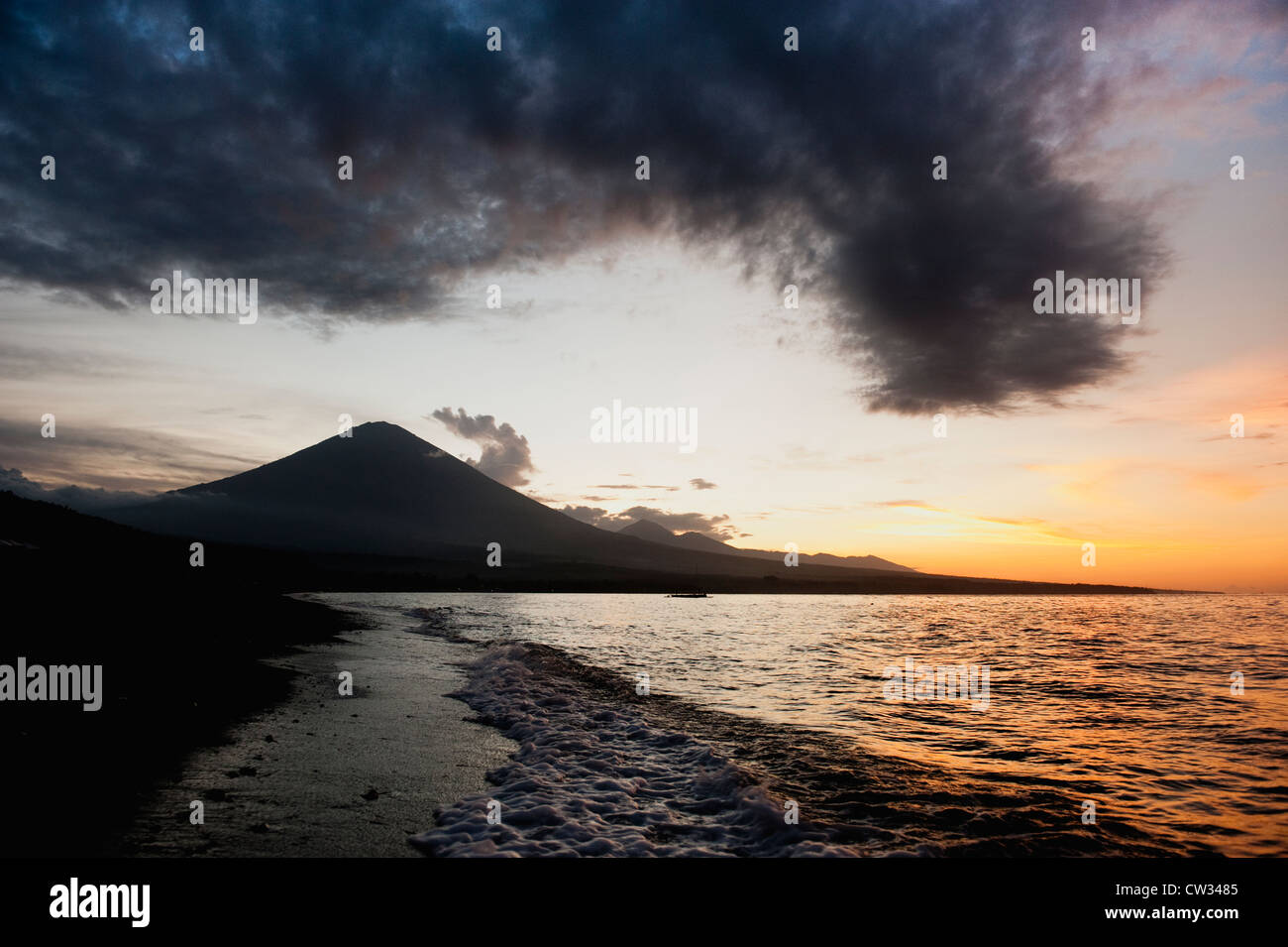 La plage de sable noir volcanique avec le volcan Gunung Agung en arrière-plan au coucher du soleil. Jemeluk, Amed, à l'Est de Bali, Indonésie. Banque D'Images