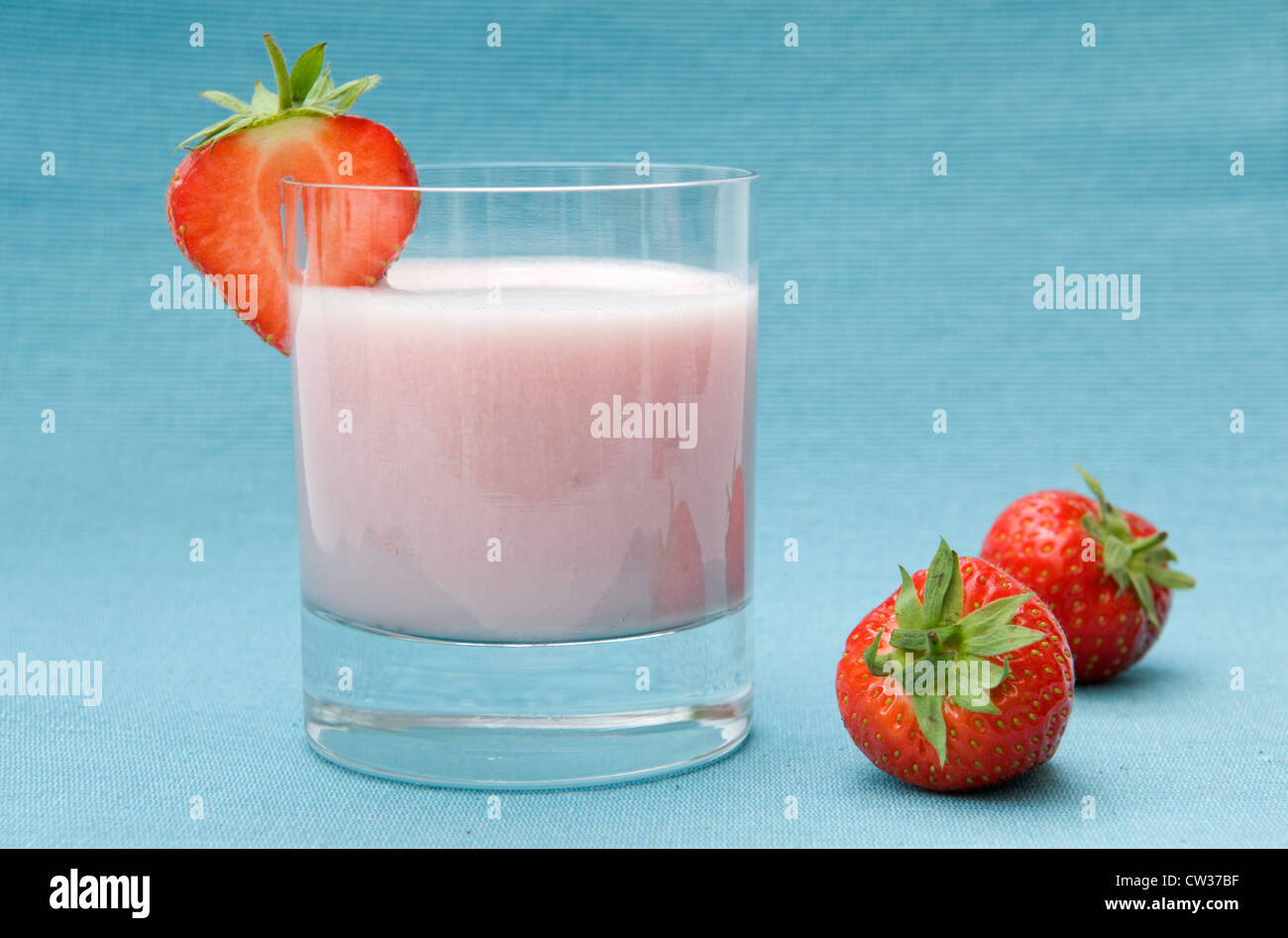 Lait frappé aux fraises faites avec des fraises fraîches, avec tranche de fraise et fraise fraîche sur le côté sur fond bleu Banque D'Images