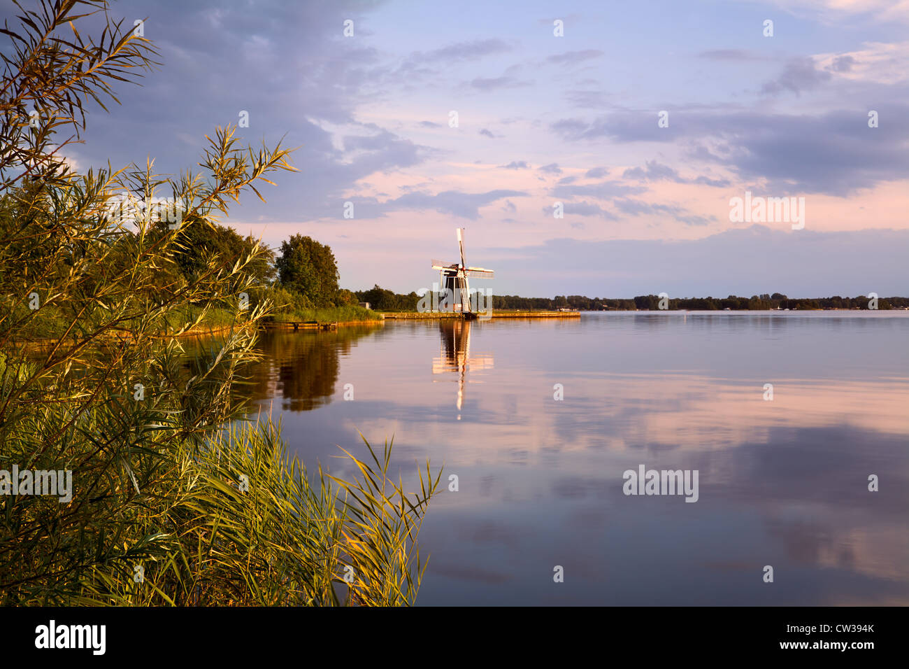 Moulin à vent hollandais sur le lac au coucher du soleil Banque D'Images