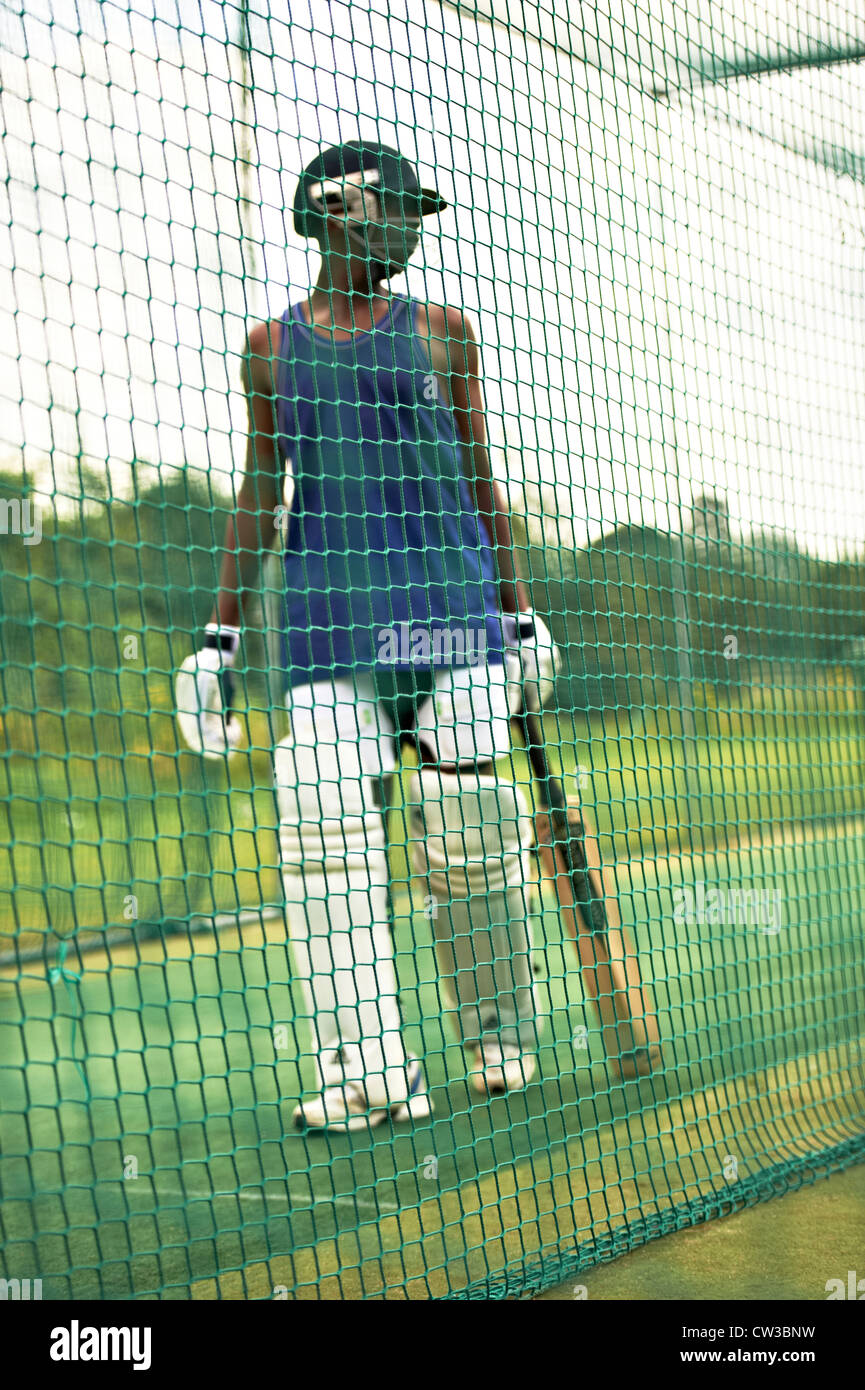 Cricketer marcher dans les filets de cricket au cours de la pratique Banque D'Images