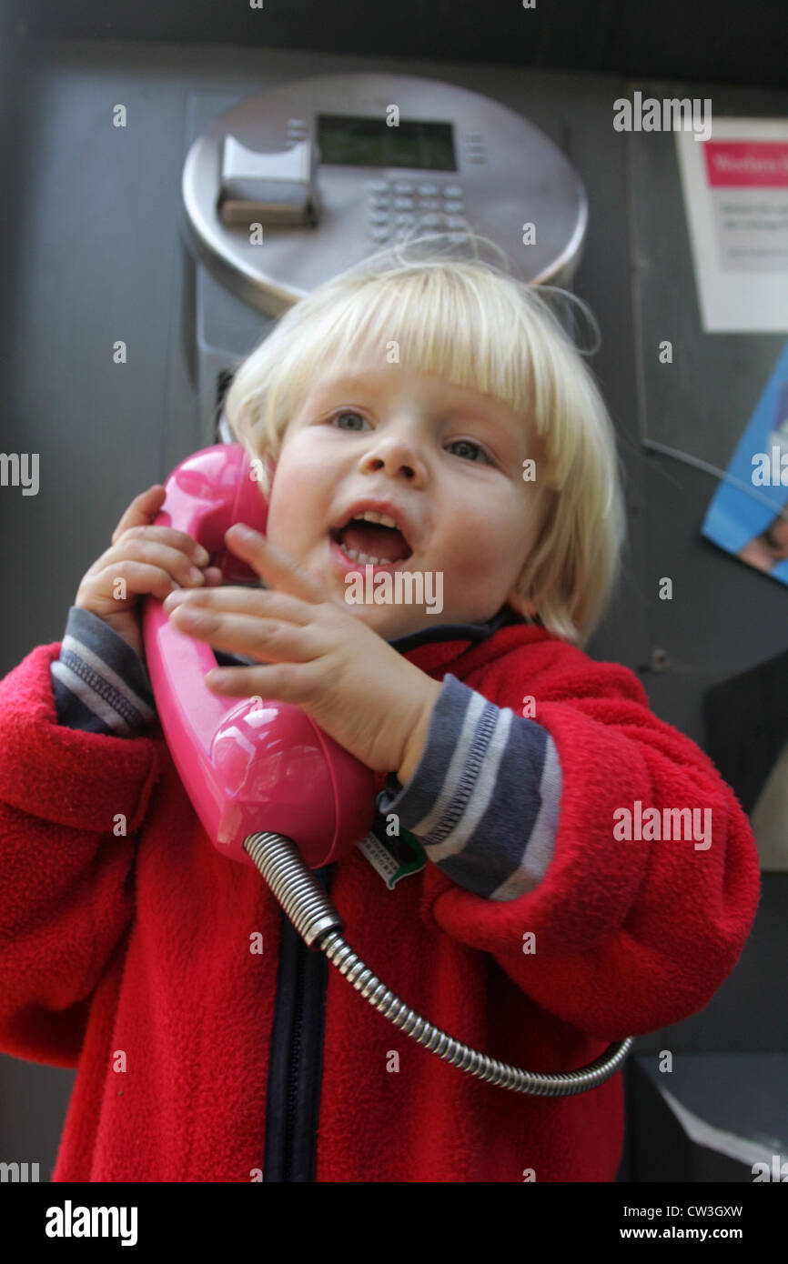 Berlin, un bambin sur le téléphone dans une cabine téléphonique Banque D'Images