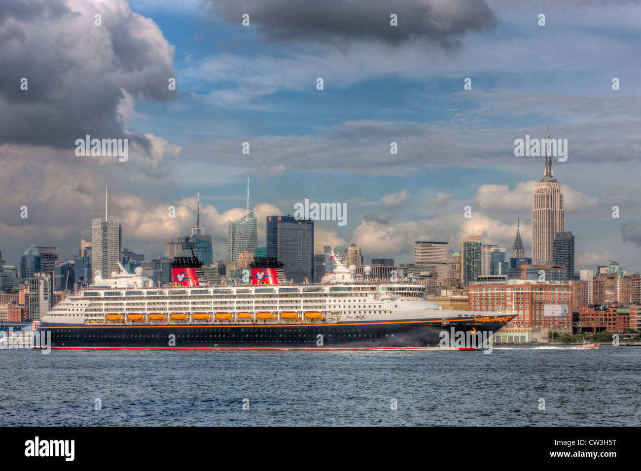 Navire de ligne de croisière de Disney Disney Magic se dirige vers le sud sur la rivière Hudson passé le New York City skyline, sous un ciel menaçant. Banque D'Images