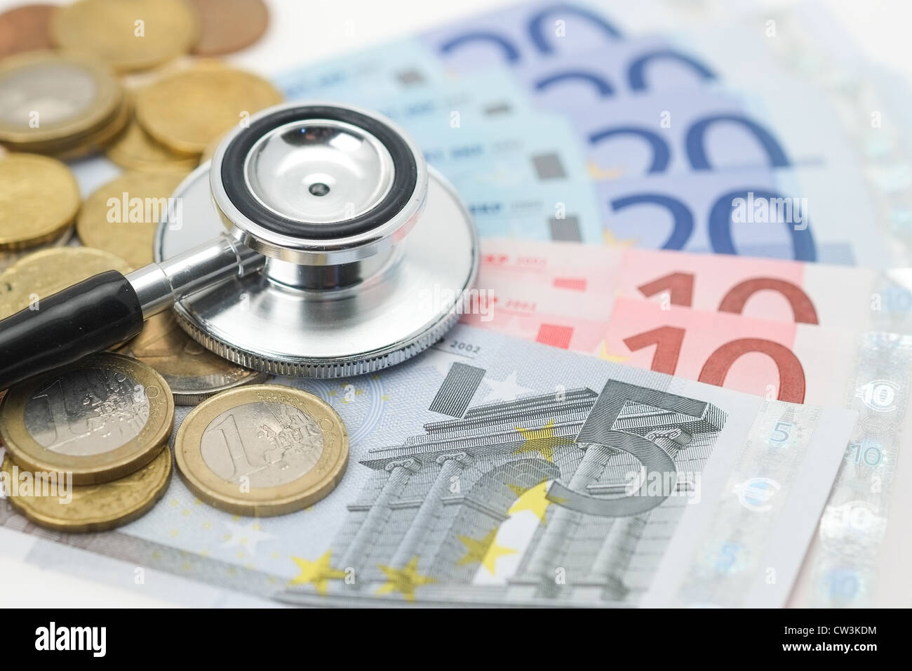 Un stéthoscope médical placé sur les pièces et billets de l'euro. Banque D'Images