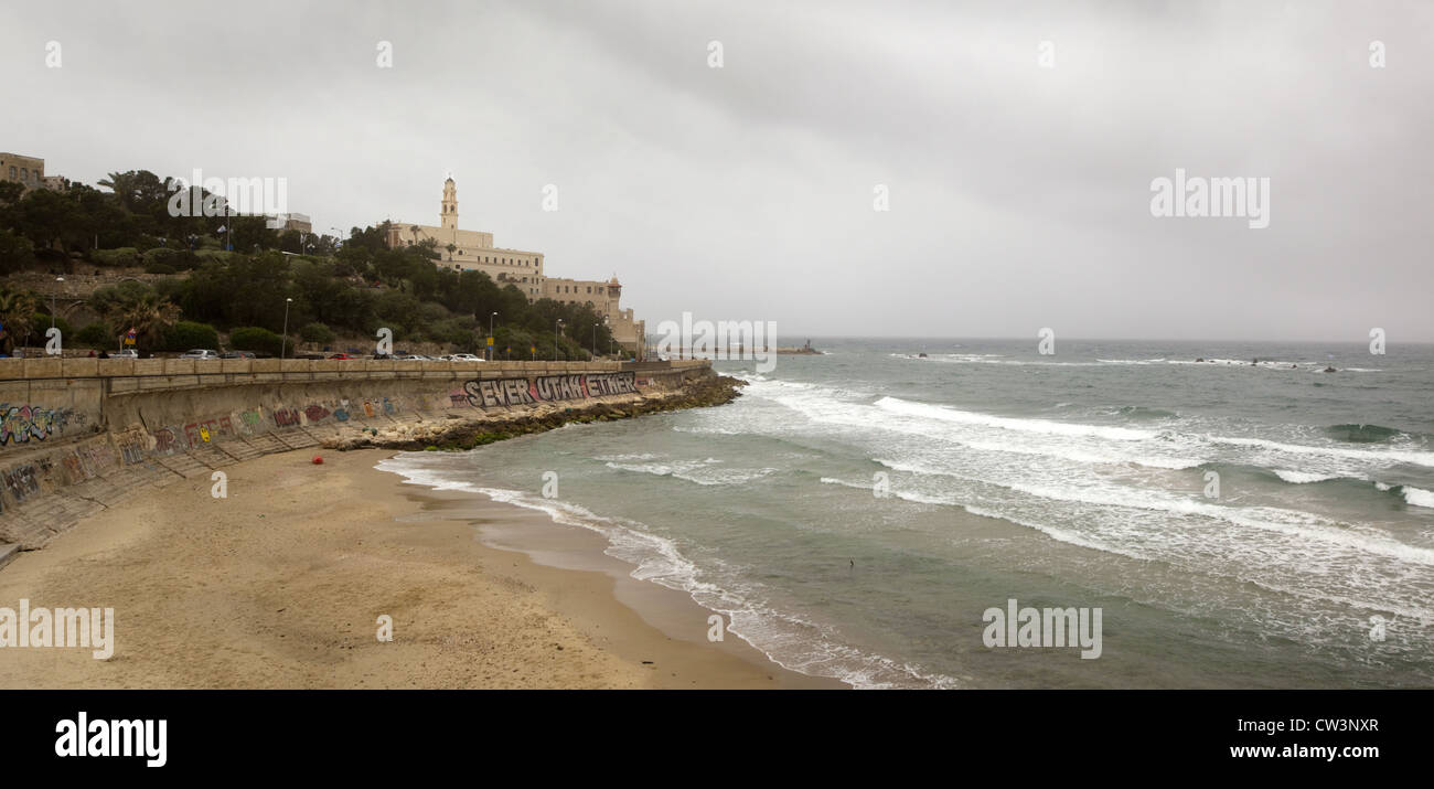 Une digue avec graffiti, plage, Église Saint Pierre, et le minaret de la mosquée al-Bahr dans la vieille ville de Jaffa, Israël Banque D'Images