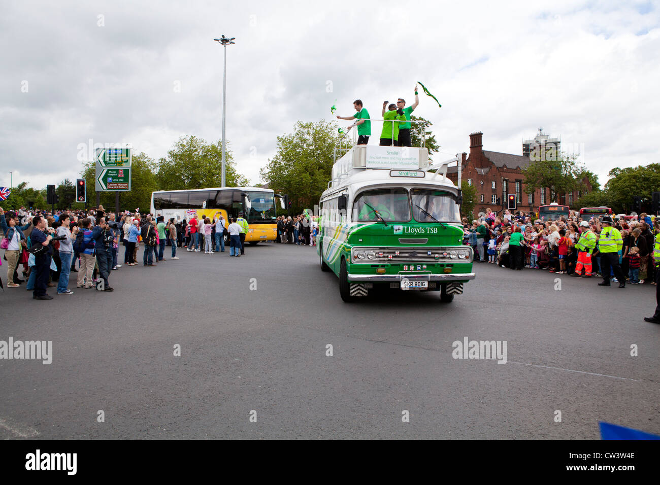 Foules bordent les rues de Birmingham, West Midlands pour attendre le passage de la flamme olympique et son porteur précédé de sponsors Banque D'Images