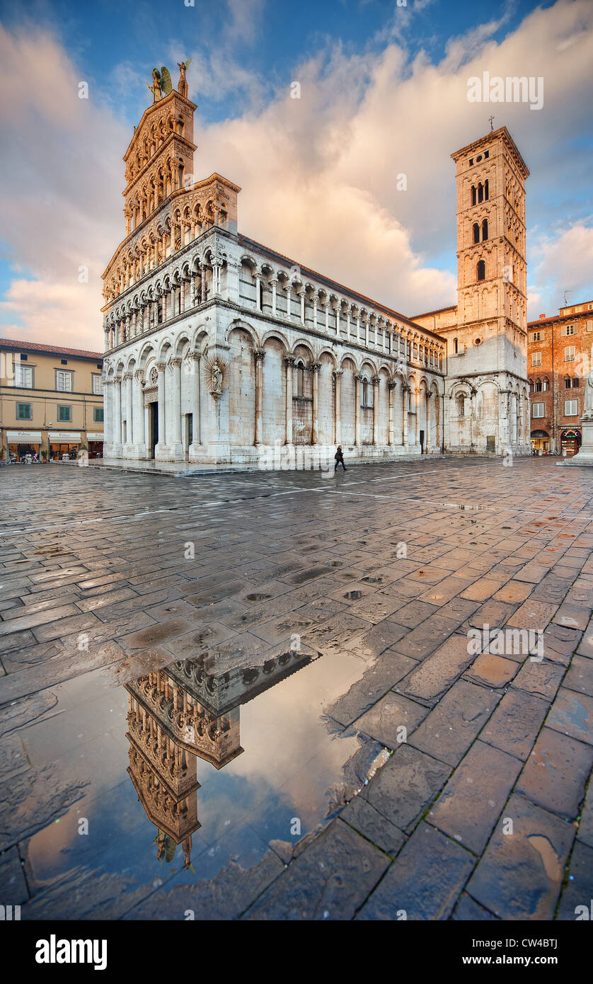 L'église de San Michele in Foro à Lucca, Italie se reflète dans une flaque à temps le soir. Banque D'Images