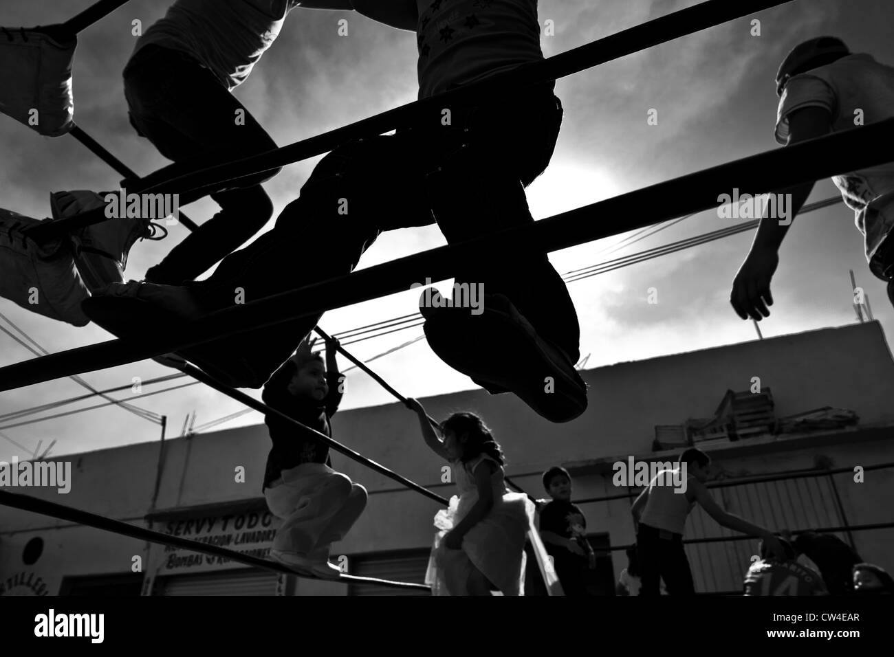 Mexican Kids jouer sur les cordes de l'anneau avant un combat dans une arène locale dans la ville de Mexico, Mexique. Banque D'Images