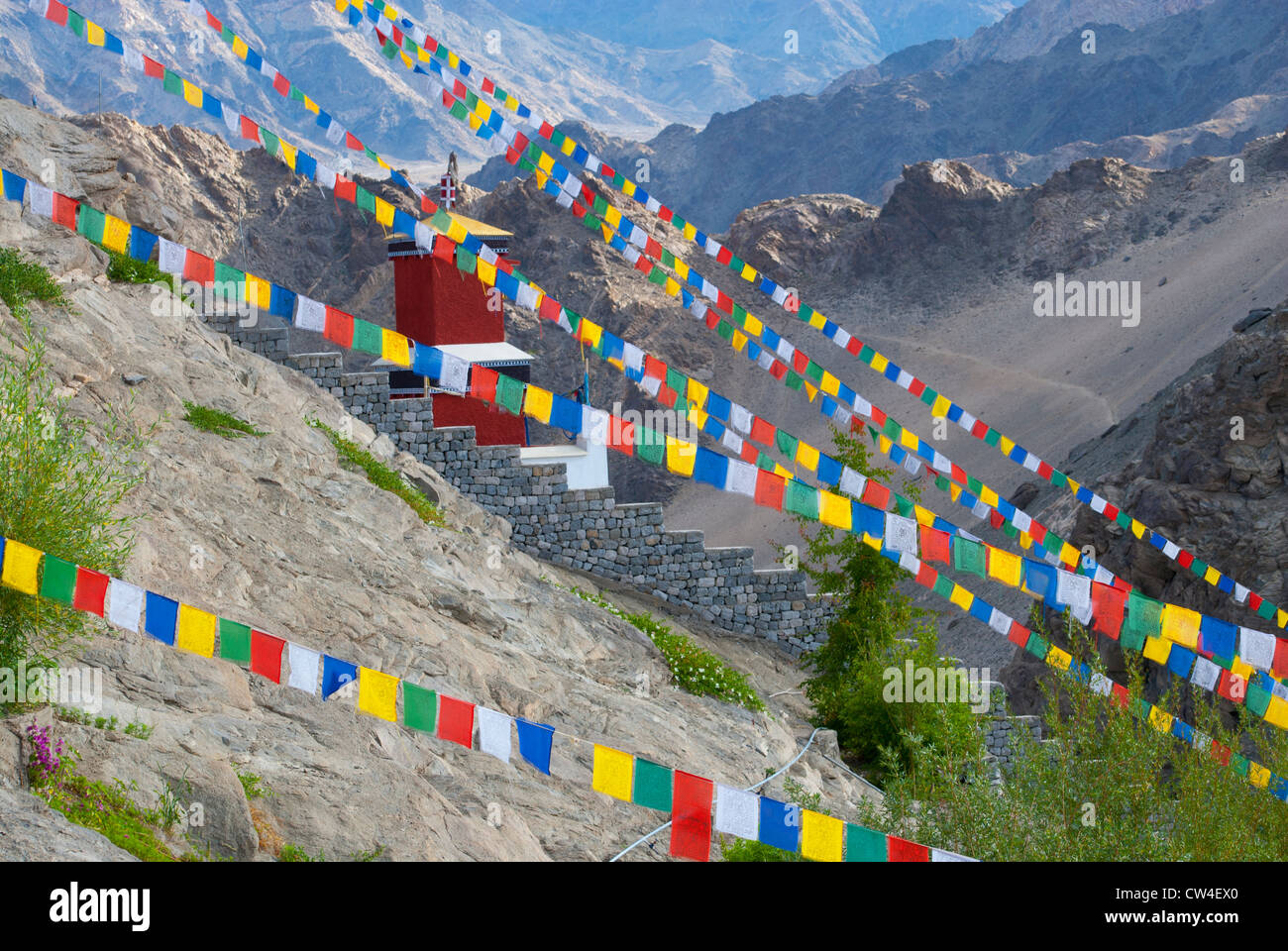 Les drapeaux de prières en face d'un bâtiment rouge avec des montagnes en arrière-plan au monastère de Thiksey près de Leh, Ladakh, Inde Banque D'Images