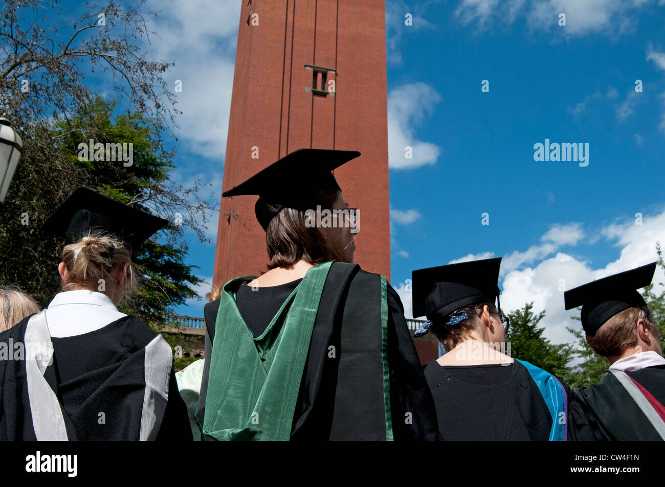 Vue arrière des chapeaux de tableau de mortier et des robes des étudiants en médecine diplômés à l'université de Birmingham Royaume-Uni avec l'ancienne tour d'horloge de joe Banque D'Images