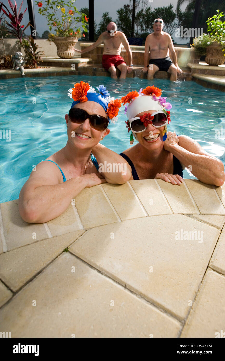 Portrait of cheerful senior femmes dans la piscine tandis que les hommes âgés assis sur un Banque D'Images