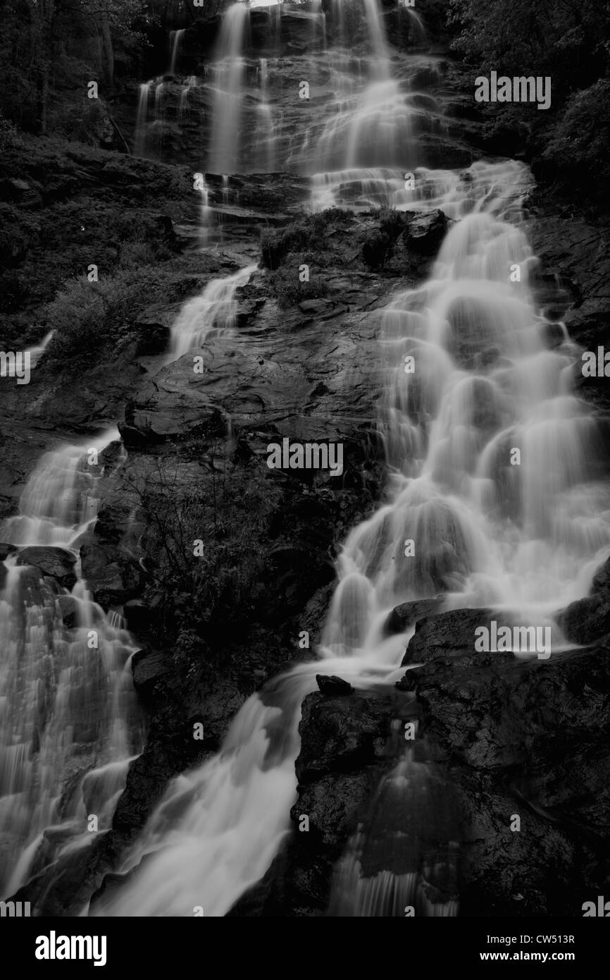 Cool, cascade rafraîchissante, descendant en rochers avec arbres et arbustes le chevet de l'eau tombant en noir et blanc Banque D'Images
