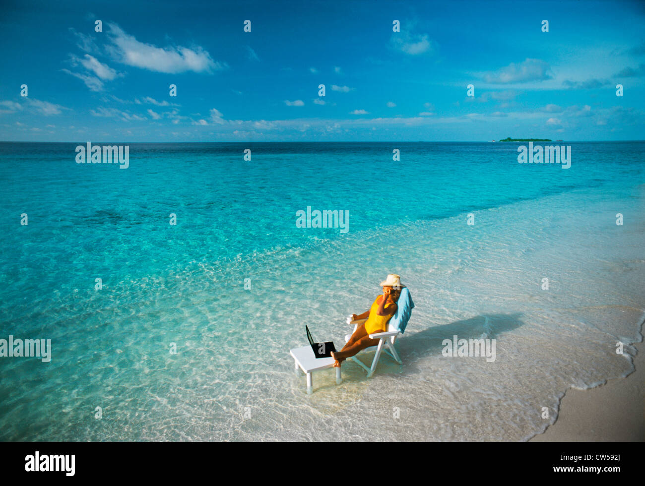 Femme assise à table avec un ordinateur portable et téléphone portable sur la plage pendant les vacances île tropicale alliant travail et plaisir Banque D'Images