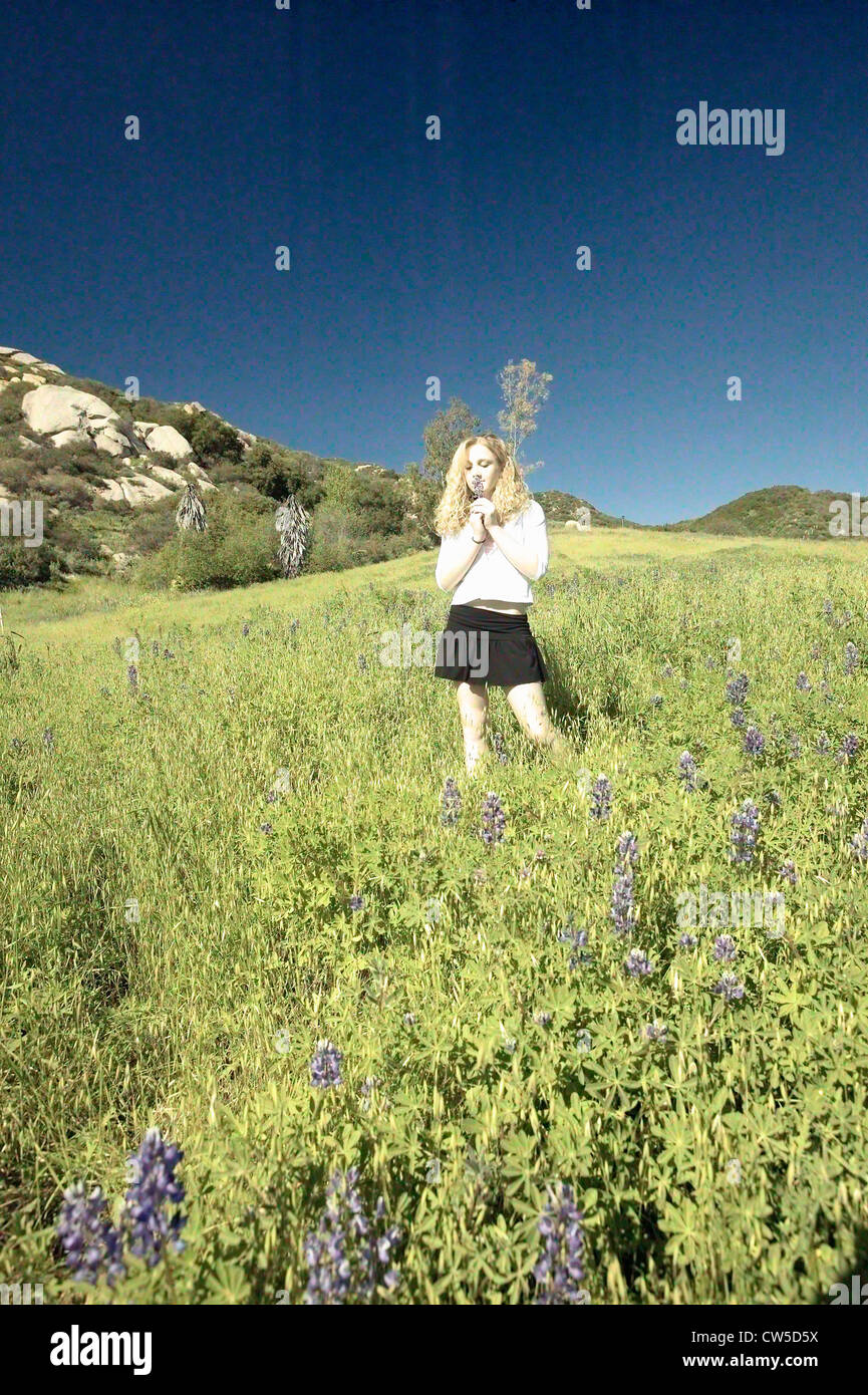 Modifié numériquement image à contraste élevé fille blonde marche à travers champs verts remplis de fleurs au printemps lupin dans Ojai CA Banque D'Images
