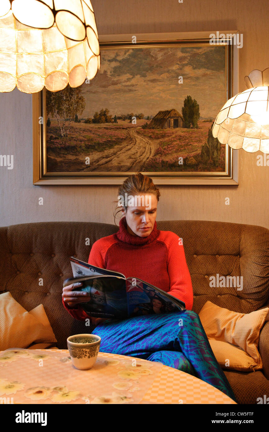 Jeune femme lisant dans une chambre avec des meubles anciens Banque D'Images