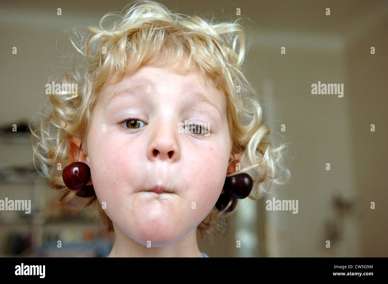 Enfant avec cerises sur l'oreille, Berlin Photo Stock - Alamy