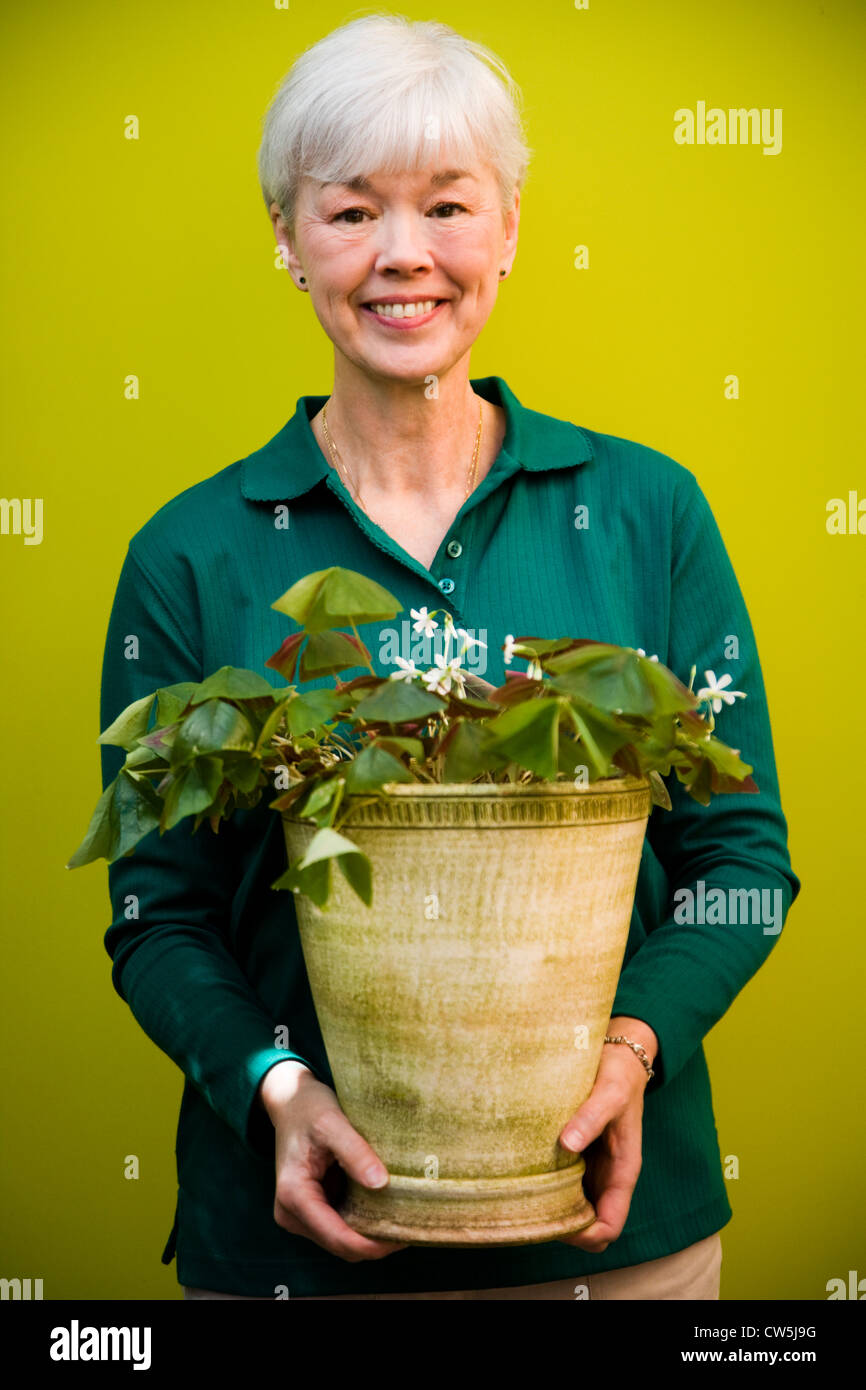 Portrait of a woman holding a potted plant and smiling Banque D'Images