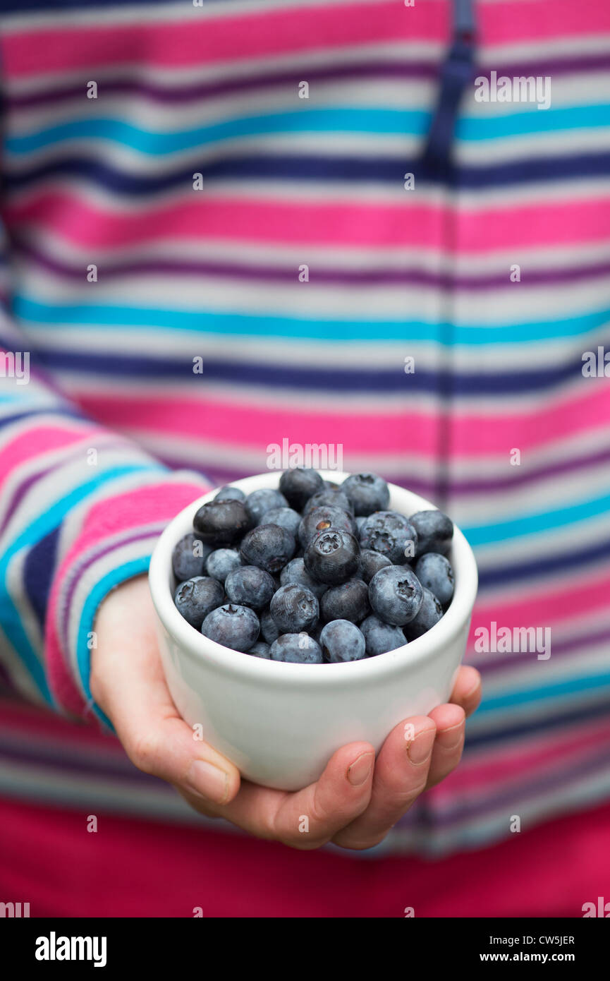 Femme portant une veste colorée tenait un bol de bleuets Banque D'Images