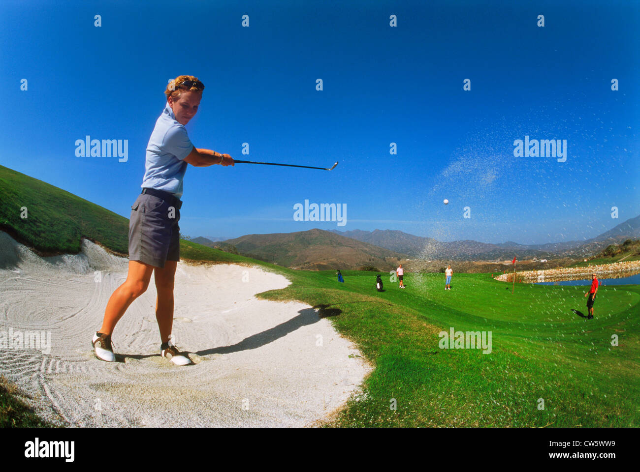 Golfeuse de frapper hors de fosse de sable sur vert sur parcours nord à La Cala Resort de Malaga sur la Costa del Sol, Espagne Banque D'Images