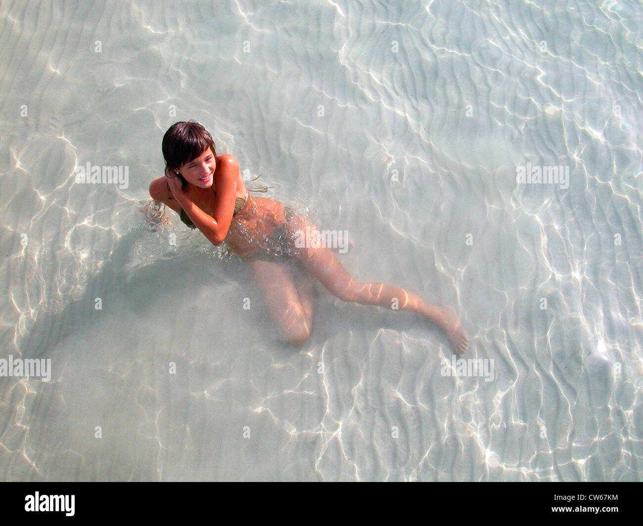 Cute young girl in bikini, slim, assis dans l'eau peu profonde de la mer, Espagne, Baléares, Majorque Banque D'Images