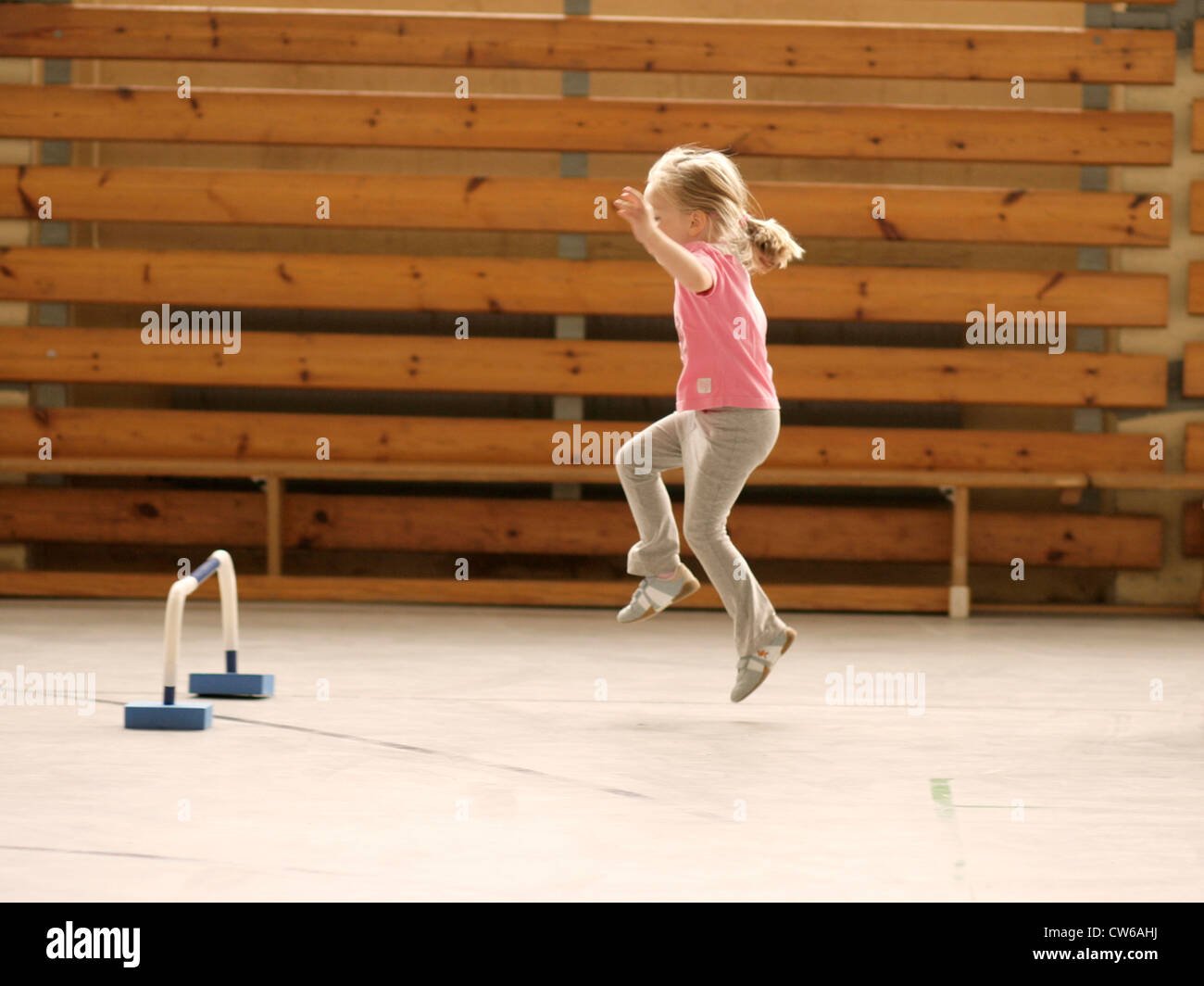 Petite fille sautant dans une salle de sport Banque D'Images
