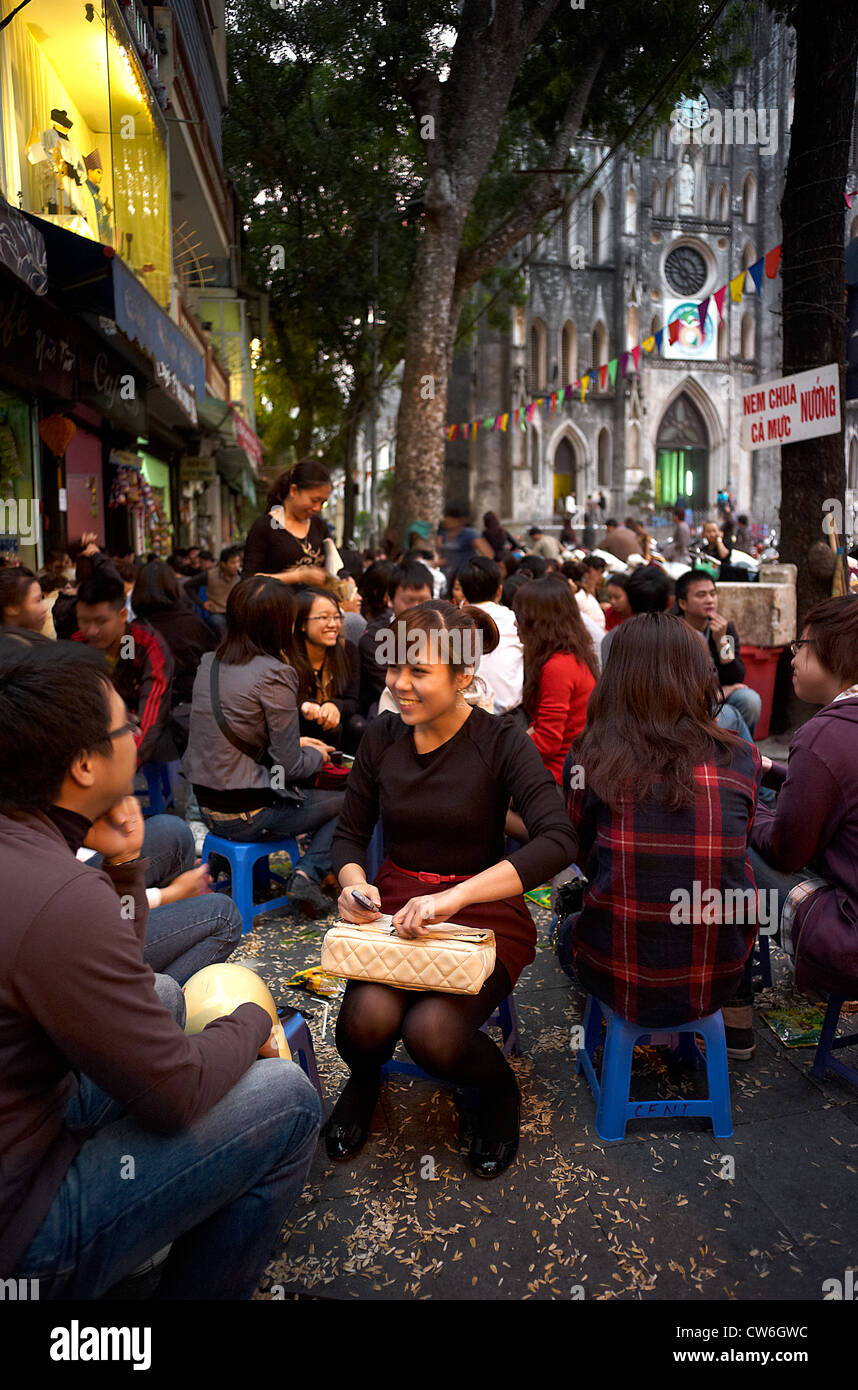 Une foule de gens assis dans la rue devant un café en plein air avec l'ancienne cathédrale St Joseph dans l'arrière-plan. Banque D'Images