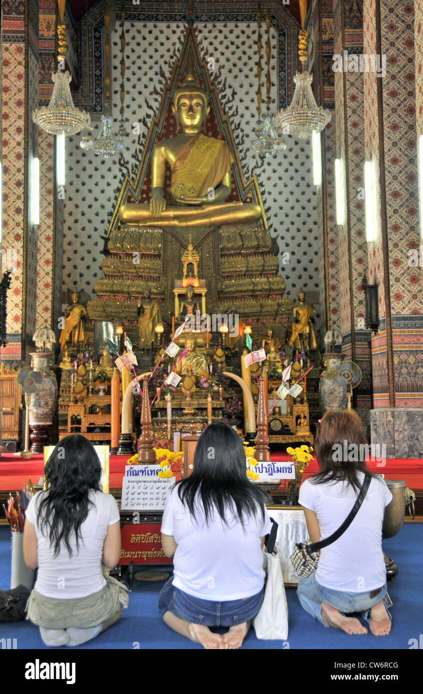 Trois femmes qui se nourrissent en face d'une statue de Bouddha, de la Thaïlande, Bangkok Banque D'Images