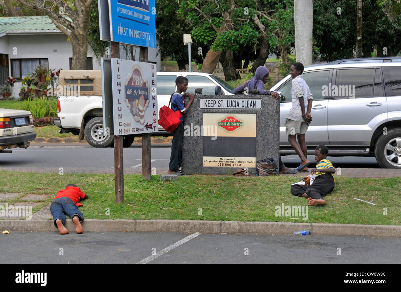 Adolescent camelots qui vendent les sculptures en bois de touristes prennent une pause sur une piste en herbe, Afrique du Sud, Santa Lucia Banque D'Images