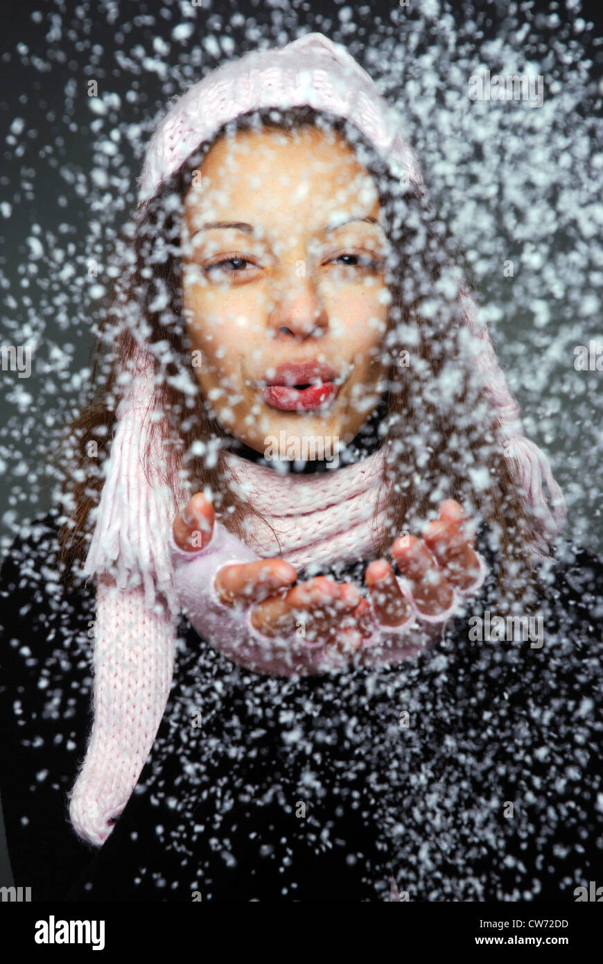 Jeune femme portant des gants et chapeau pointu, souffle loin de la neige artificielle Banque D'Images