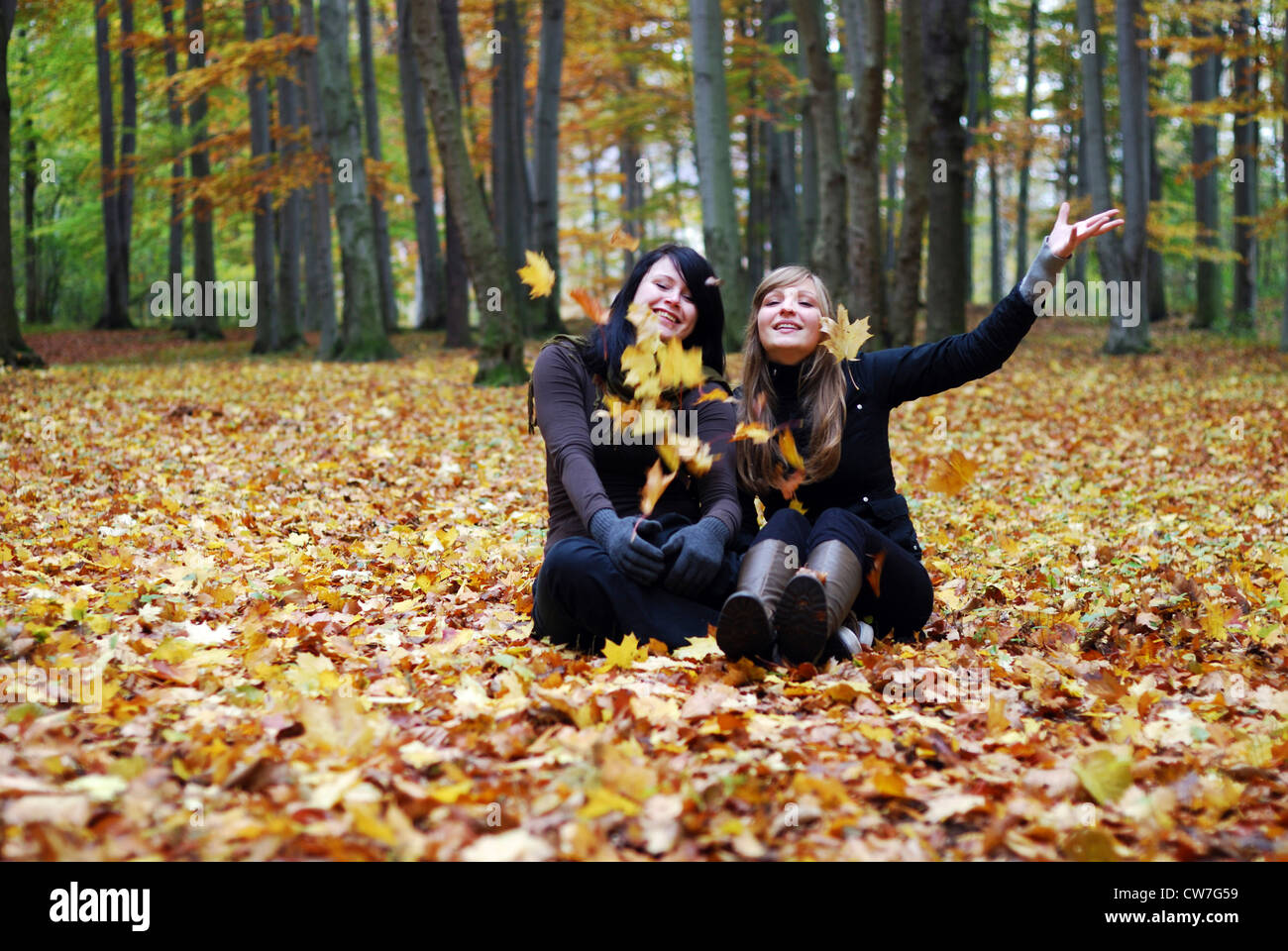 Deux copines dans la forêt , assis et jeter quelques feuilles Banque D'Images
