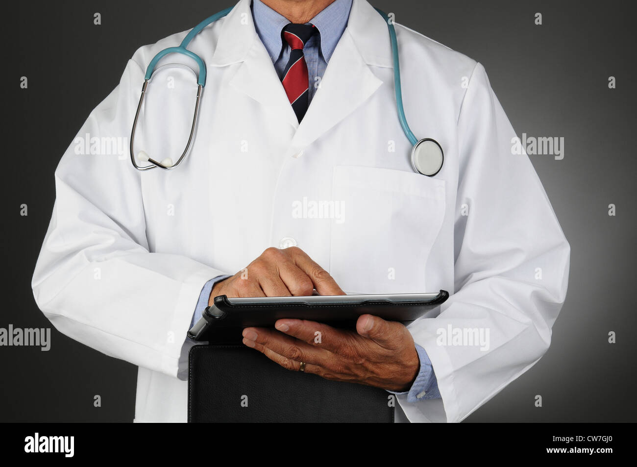 Libre d'un médecin à l'aide d'un ordinateur tablette. Format horizontal sur une lumière sur fond gris foncé. L'homme est méconnaissable. Banque D'Images