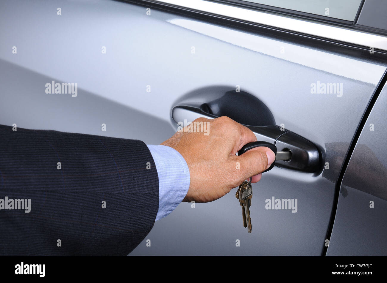 Libre de la main d'un homme de l'insertion d'une clé dans la serrure d'une voiture. Format horizontal. Voiture et l'homme sont méconnaissables. Banque D'Images