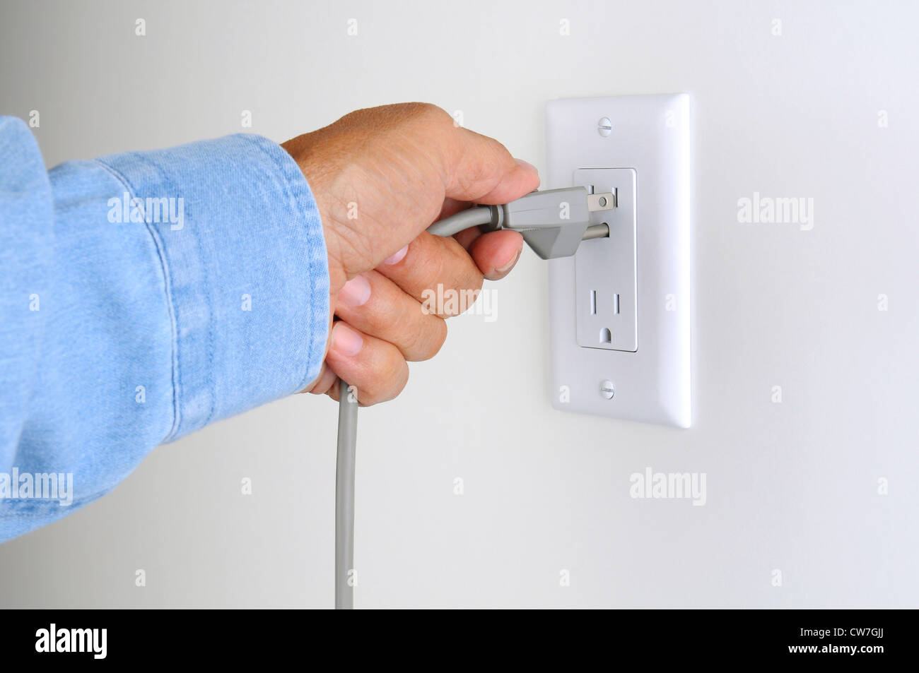 Libre d'une main d'homme l'insertion d'une fiche électrique dans une prise de courant. Banque D'Images
