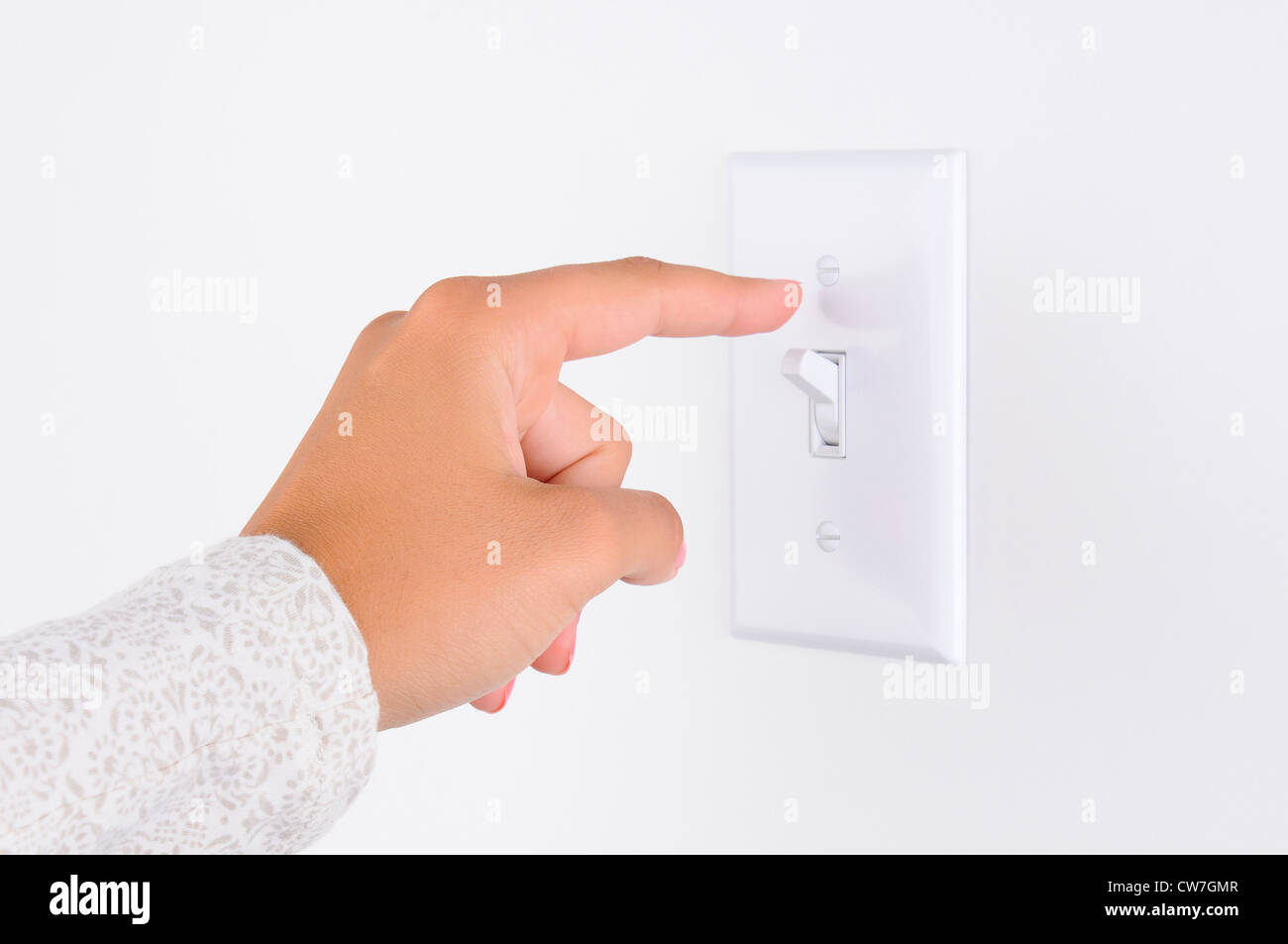 La main de femme avec le doigt sur l'interrupteur d'éclairage, sur le point d'éteindre les lumières. Libre de part et de l'interrupteur seulement. Format horizontal. Banque D'Images