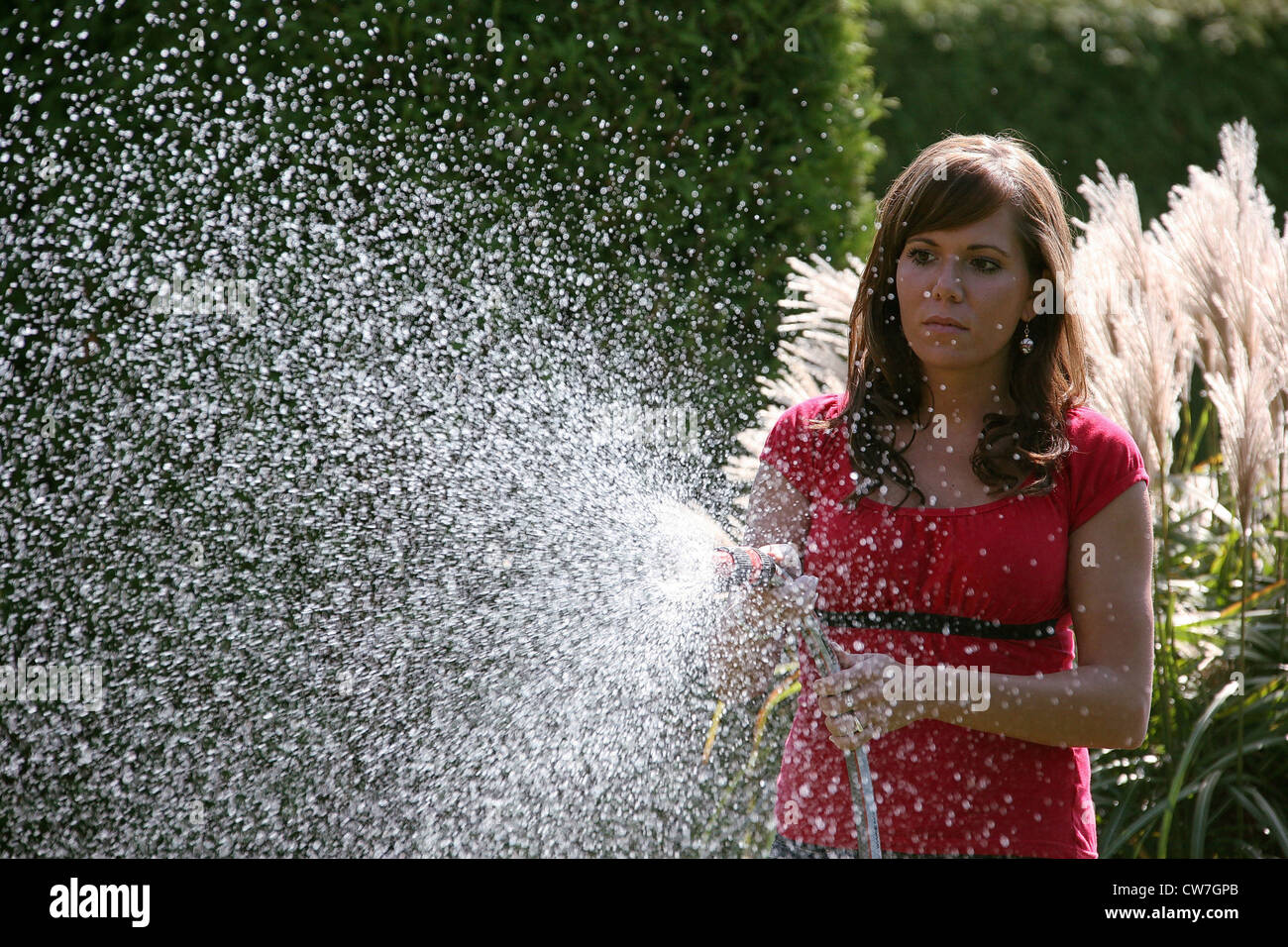 Jeune femme se déverse dans le jardin de fleurs Banque D'Images