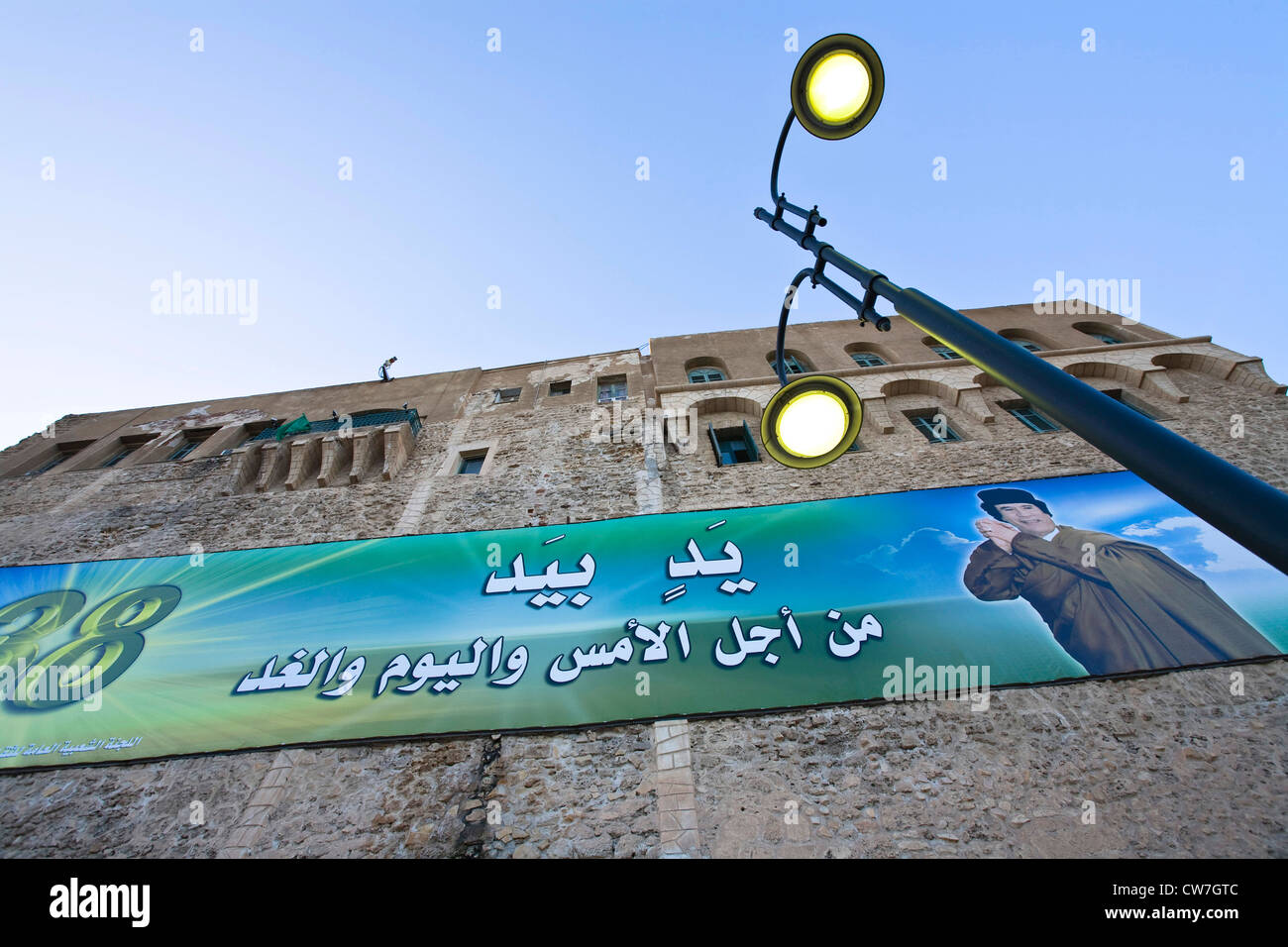 Bannière de propagande représentant chef d'Etat Kadhafi sur la façade de l'ancien château espagnol Saraya al-Hamra à partir du 16e siècle à la Place Verte, au crépuscule, en Libye, Tripoli Banque D'Images