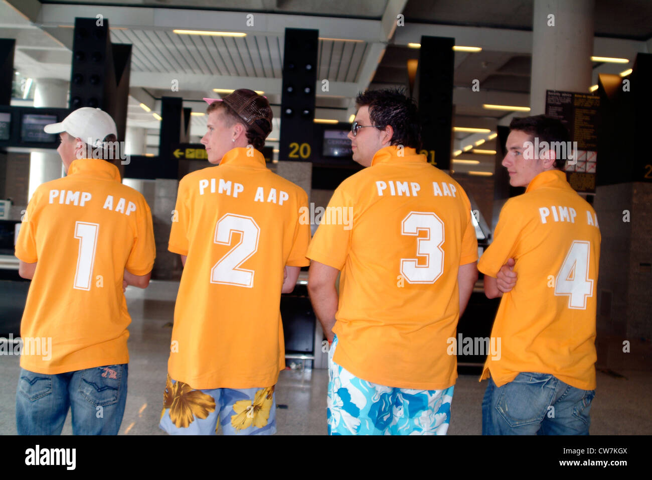 Quatre touristes avec T-Shirts numérotés consécutivement en attente pour les bagages à l'aéroport, Espagne, Baléares, Majorque Banque D'Images