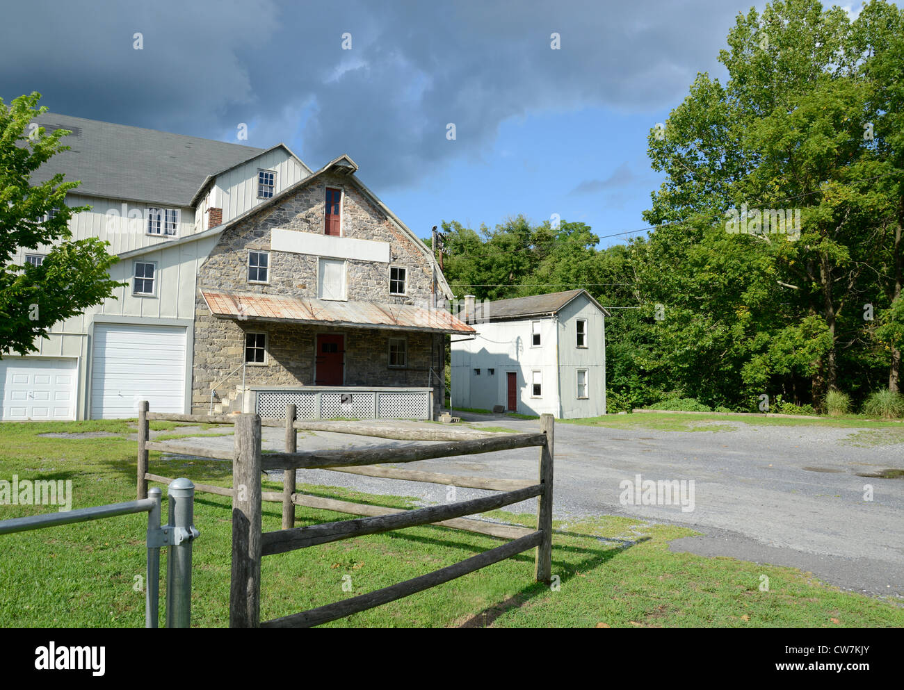 Ancienne usine d'aliments par un stationnement de gravier et l'herbe avec barrière en bois Banque D'Images