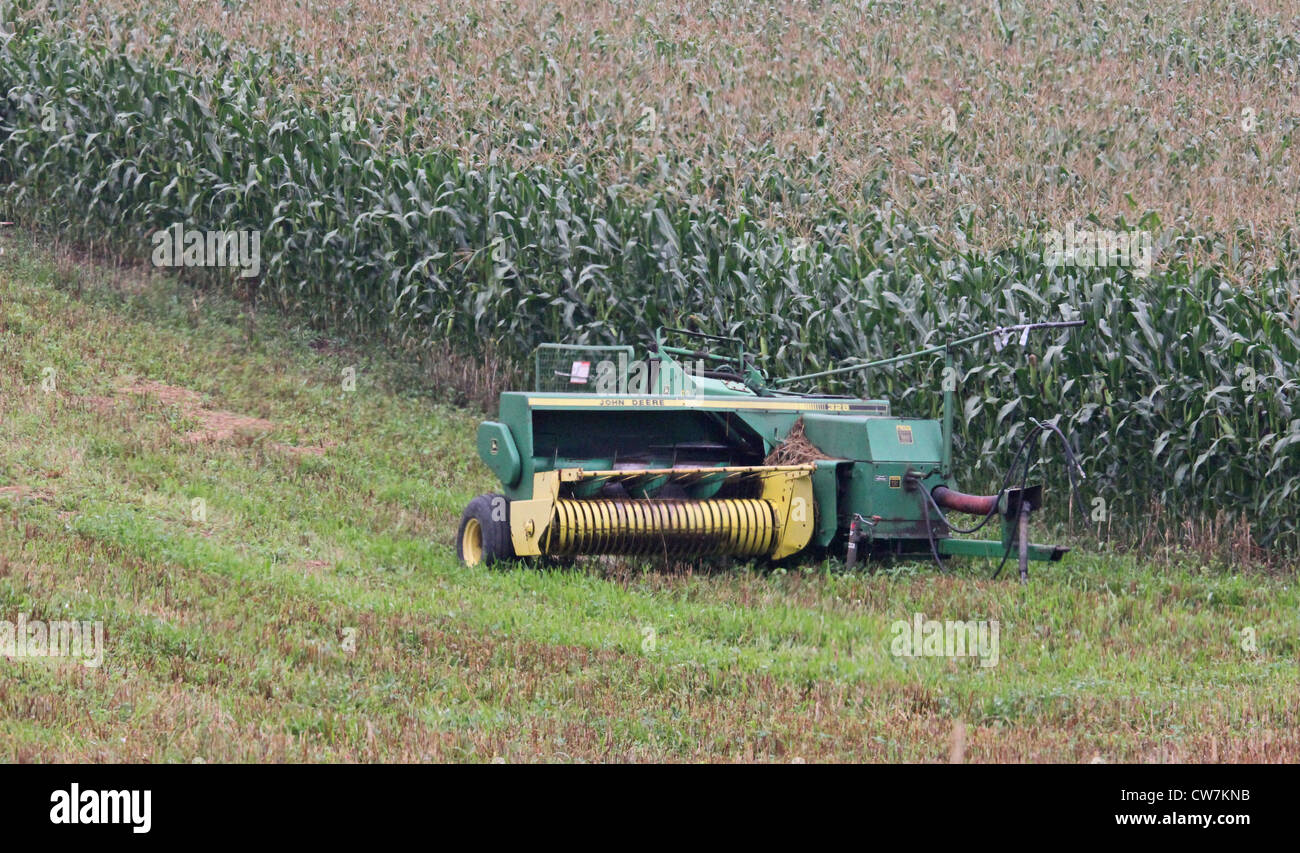 Un John Deere Ramasseuse de foin dans un champ. Banque D'Images