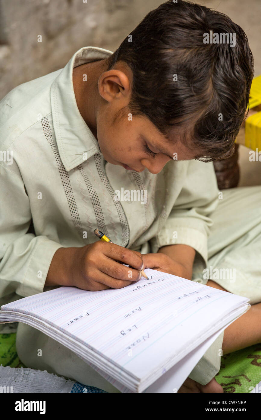 Jeune garçon pakistanais écrit en anglais dit Village Pur, Islamabad, Pakistan Banque D'Images