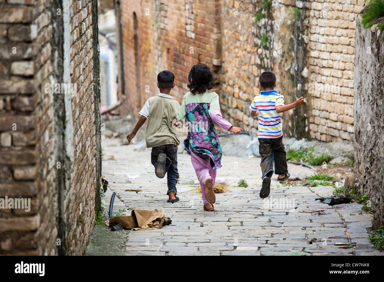 Enfants en train de courir dans une ruelle, a déclaré Village Pur, Islamabad, Pakistan Banque D'Images