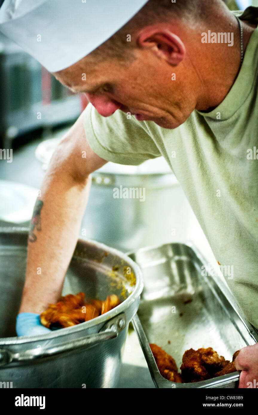 PROVINCE DE PARWAN, Afghanistan - CPS. Jeremy Newton, un Atlas de la Force opérationnelle, 82e Spécialiste du service alimentaire de la Brigade de l'aviation de combat de Sierra Vista, en Arizona, ramasse les ailes de buffle d'un pot et dans un plateau de service les ailes ont été servies à côté de steak, pieds de crabe, côtes et hamburgers pendant que le restaurant de l'aviation a vidé ses glacières et ses placards le dernier jour de travail. Ce centre populaire, qui a souvent vu des lignes de 30 minutes le vendredi soir, a fermé ses portes définitivement le 17 août. Banque D'Images