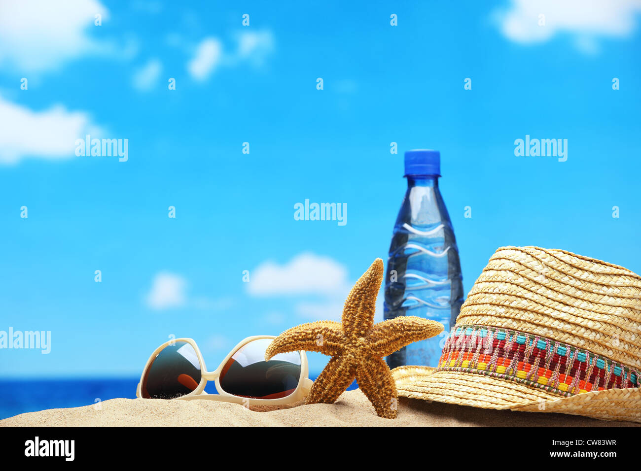 Bouteille d'eau,chapeau de paille,lunettes de soleil et de mer sur plage de sable fin. Banque D'Images