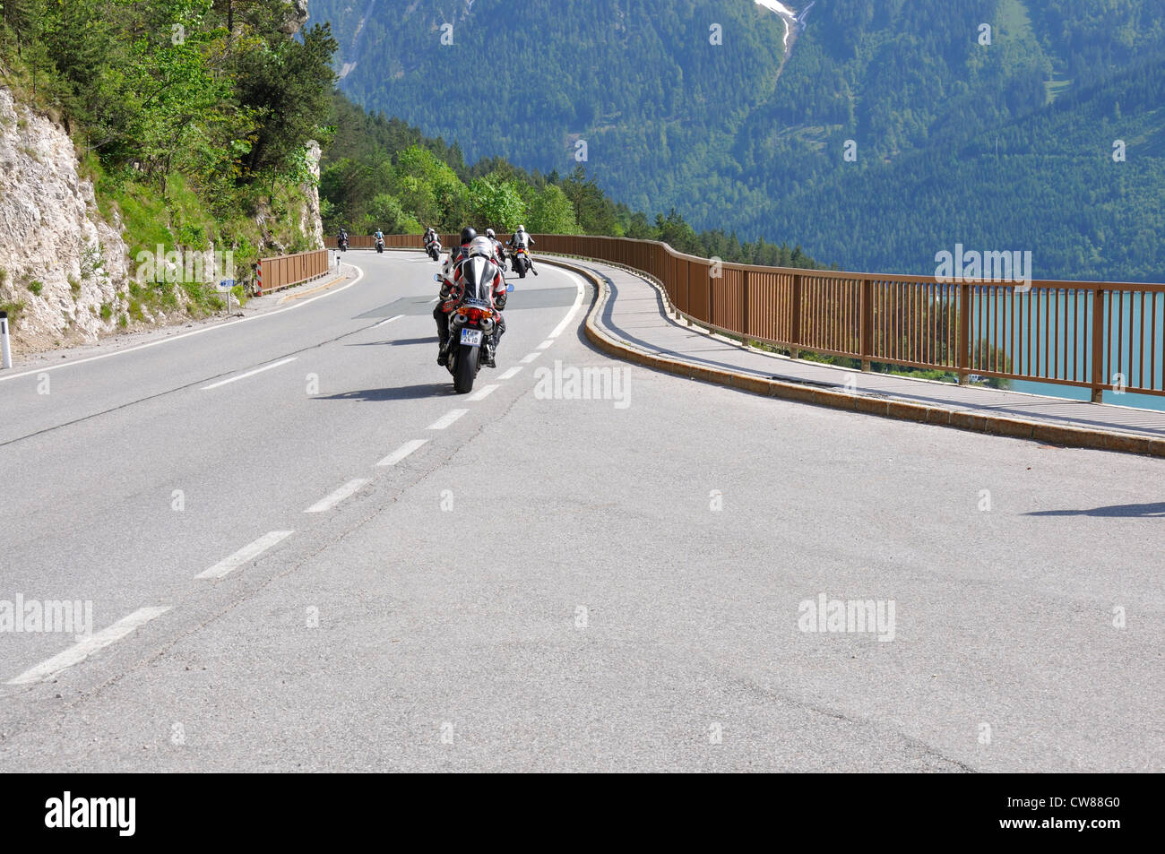 Les personnes conduisant des motos sportives dans les Alpes, en montant une côte route de montagne Banque D'Images