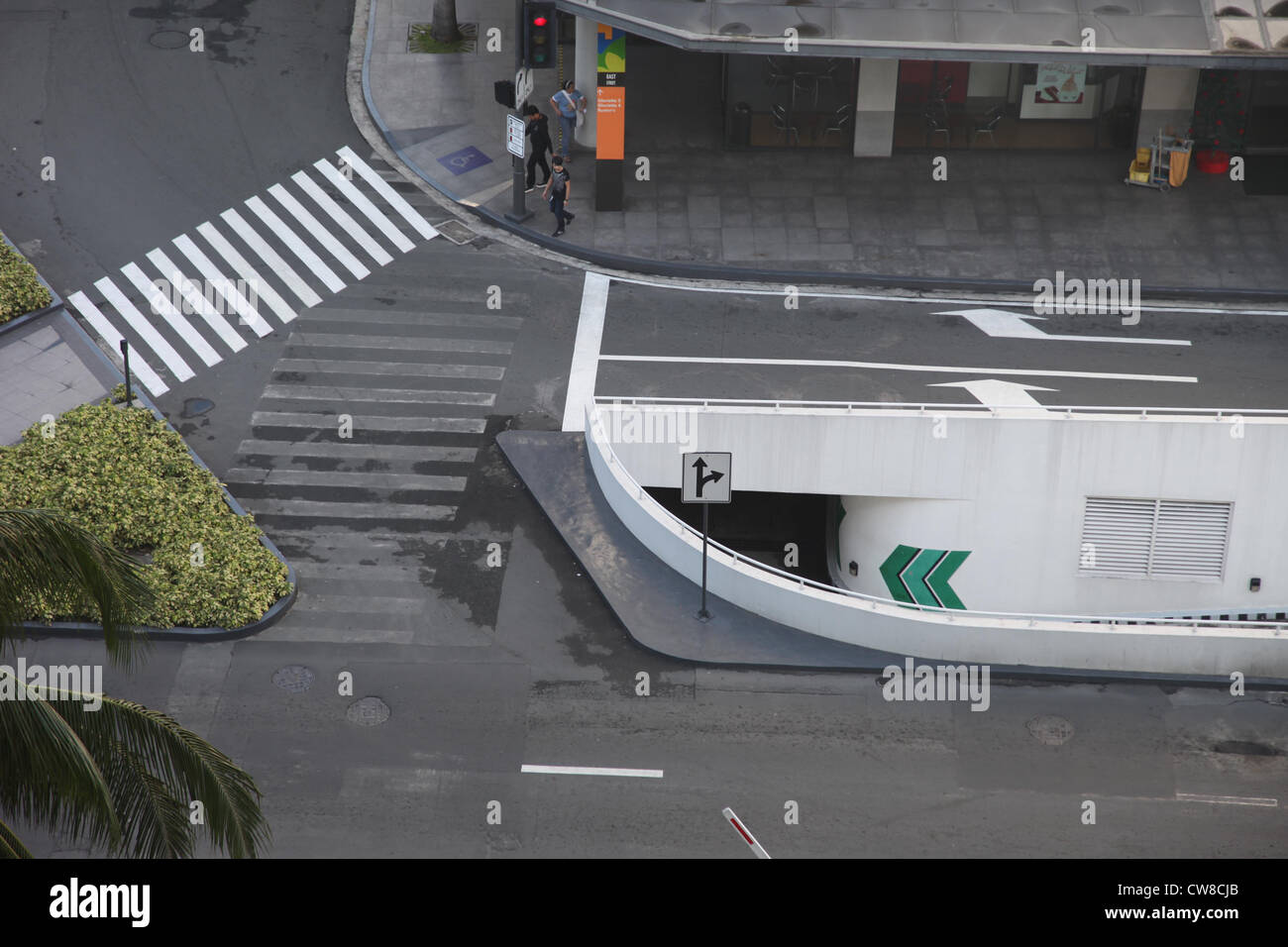 C'est une photo vue du haut de la rue. Nous pouvons voir une entrée du parking. Il y a des voitures garées dans. Zebra crossing sur route Banque D'Images