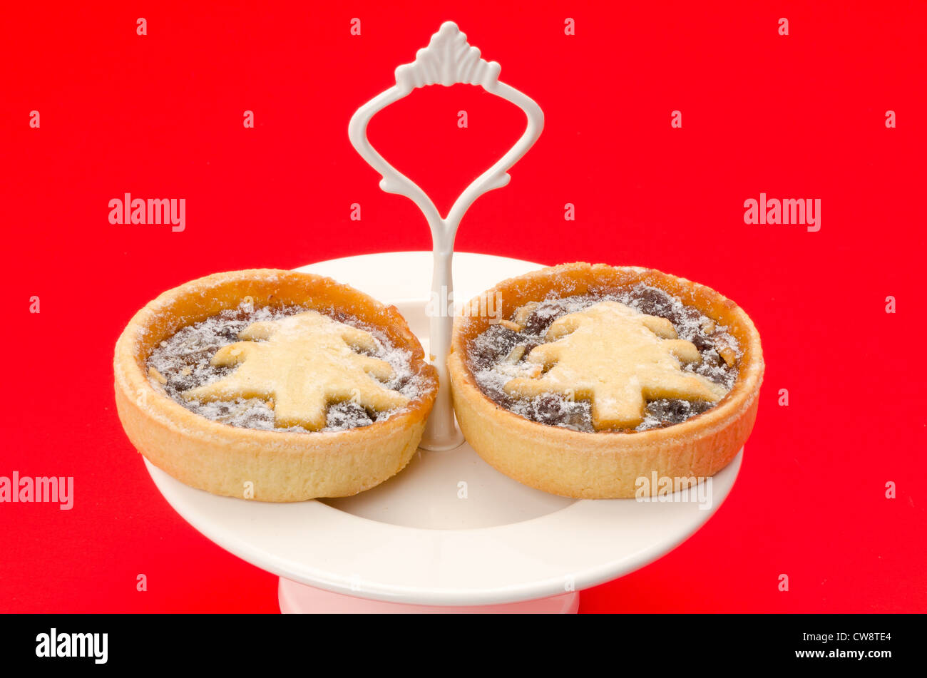 Fêtes de Noël ou petits pâtés fait maison et placé sur un plat à gâteau - studio photo avec un fond rouge Banque D'Images